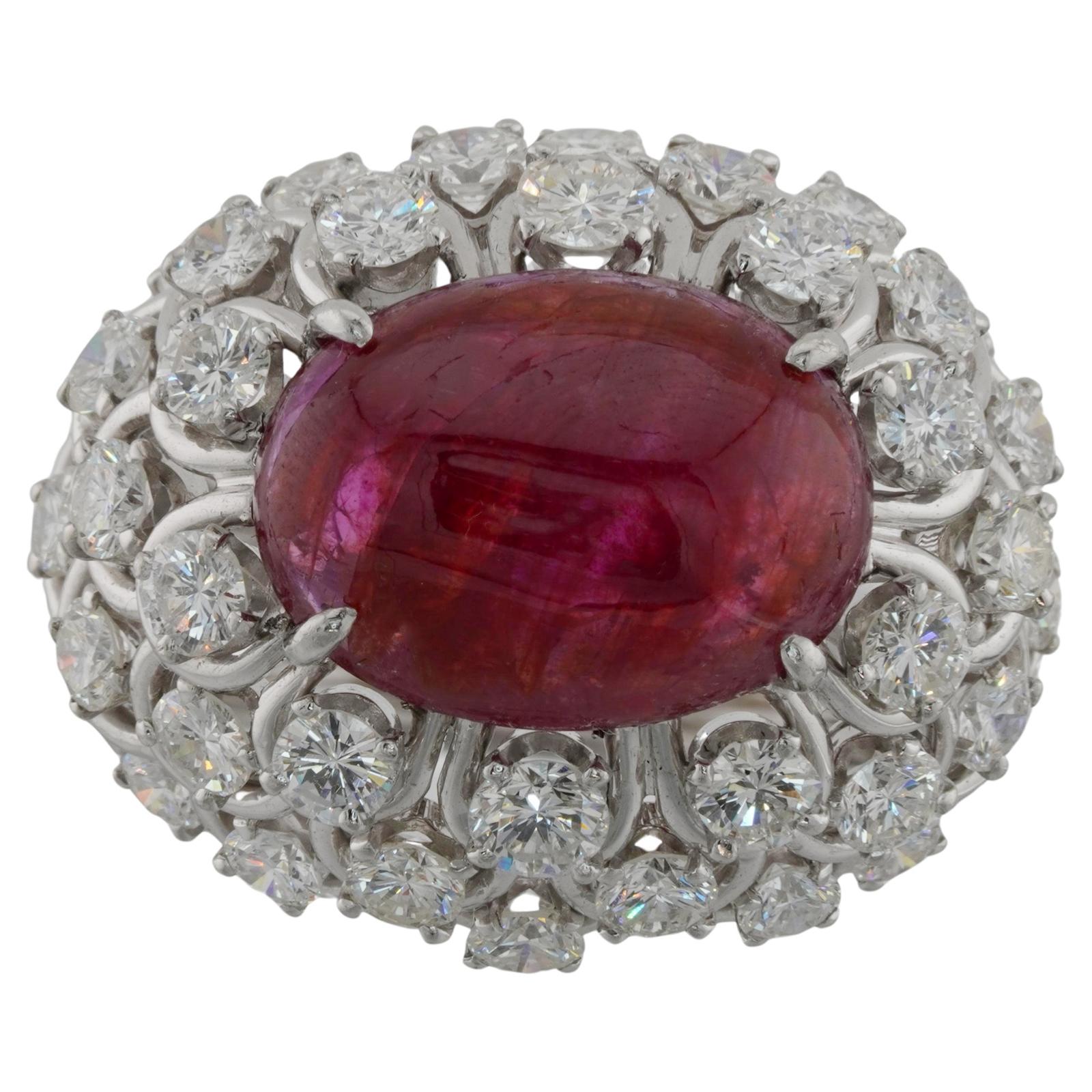 Cette bague captivante de David Webb présente une couronne en forme de dôme au design ouvert, sertie d'un rubis cabochon ovale de 11,0 mm x 15,0 mm et entourée de 36 diamants ronds étincelants. Réalisé en platine fin, il est complété par un ressort