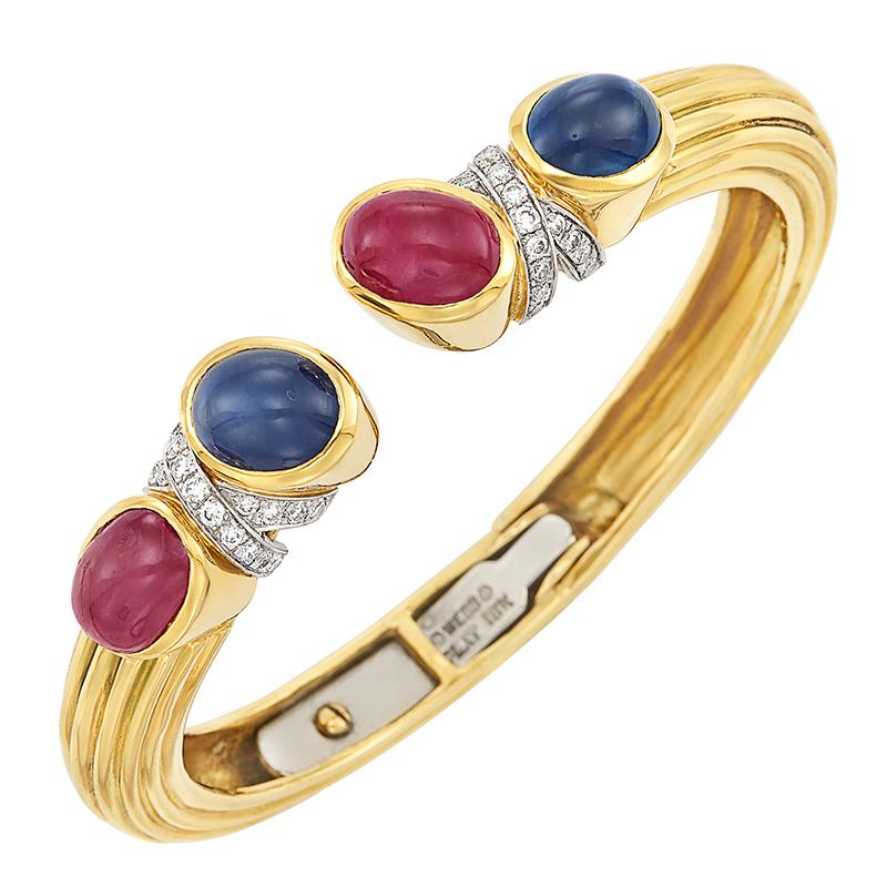 David Webb Cabochon Ruby & Sapphire 18k gold Bracelet, circa 1975.
18 kt., the ribbed bangle centering 4 oval cabochon rubies and sapphires, spaced by platinum-set X's of 38 round diamonds approximately .75 ct., signed Webb, approximately 31.6 dwts.