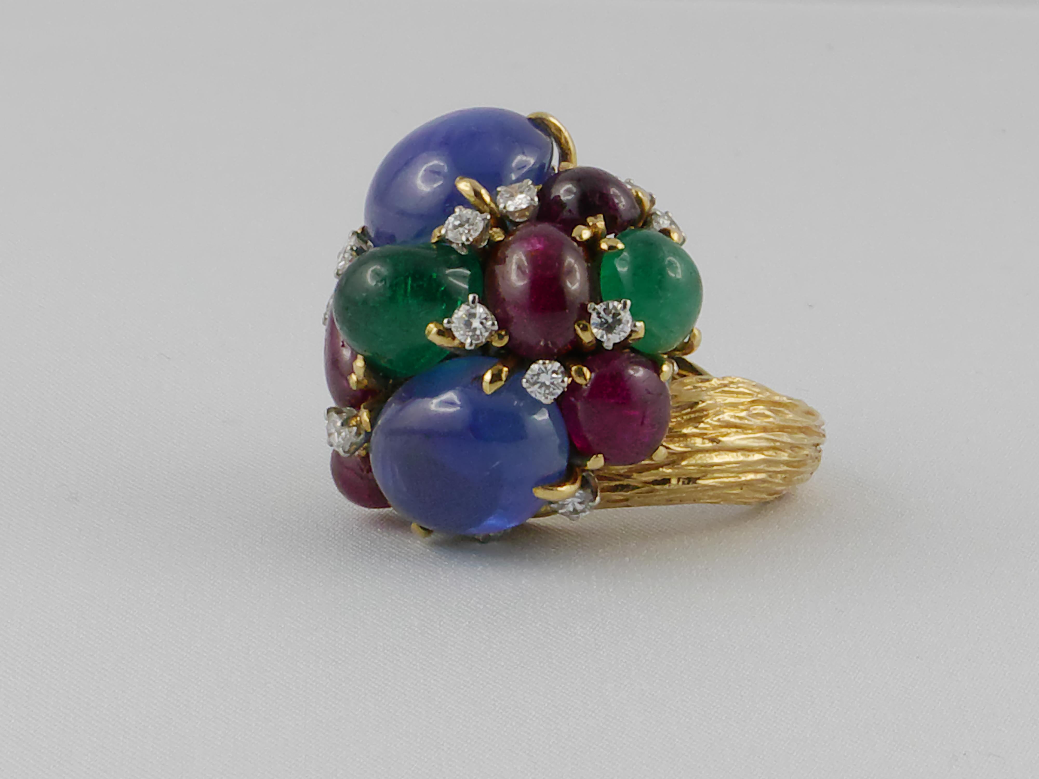 David Webb dramatic color contrast cocktail ring in18 karat yellow gold and platinum with  6 cabochon Rubies, 2 wide cabochon Sapphires,  3  cabochon Emeralds and diamonds, weighing a total of 24 Grams.
Size: 6 1/4 – Resizable

In case of return of