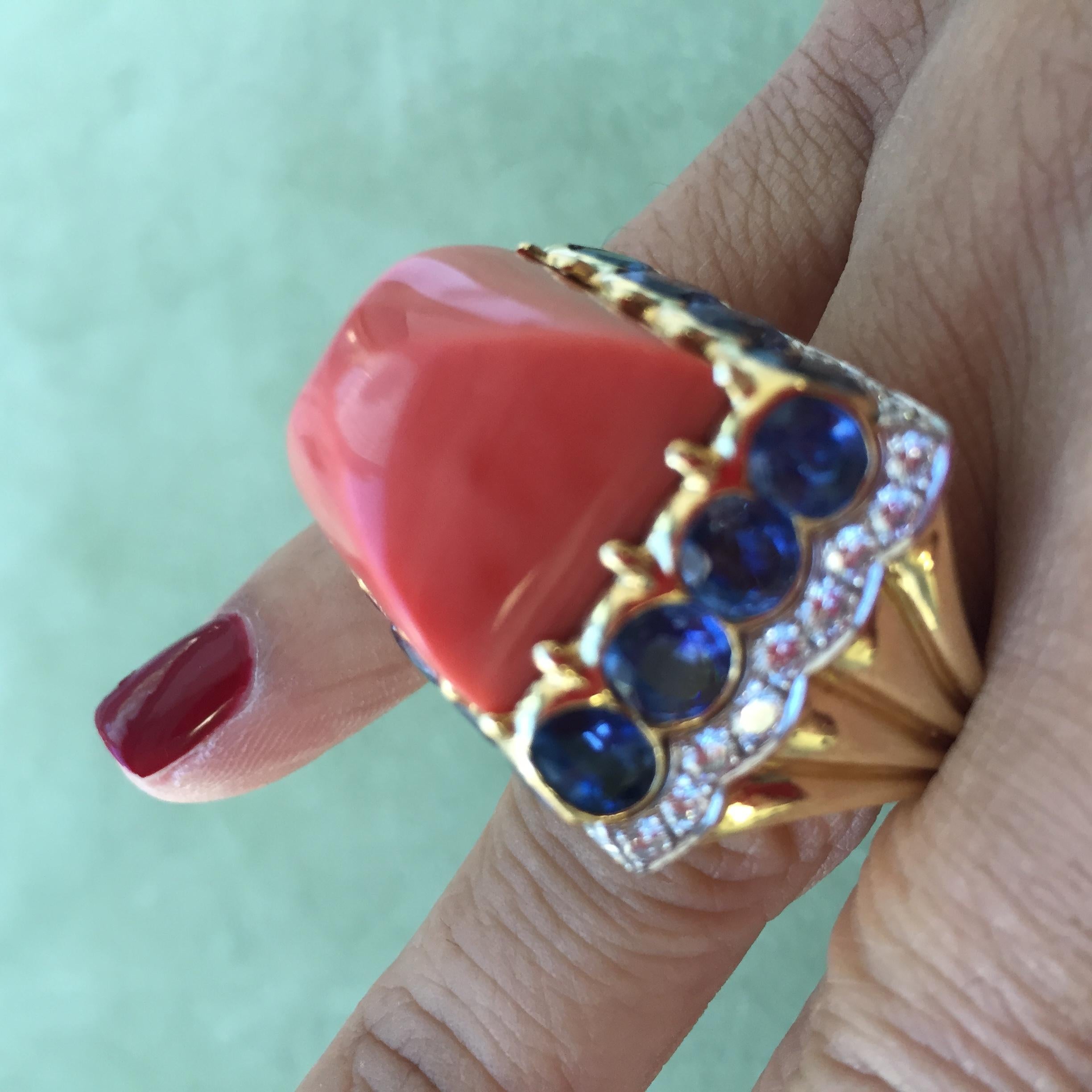 David Webb Colors Coral Sapphire Diamond Ring in 18k Yellow Gold and Platinum.

An extravagant ring emblematic to the David Webb style and attributed to the Colors collection. This ring features a carved sugarloaf coral cabochon perched atop a crown