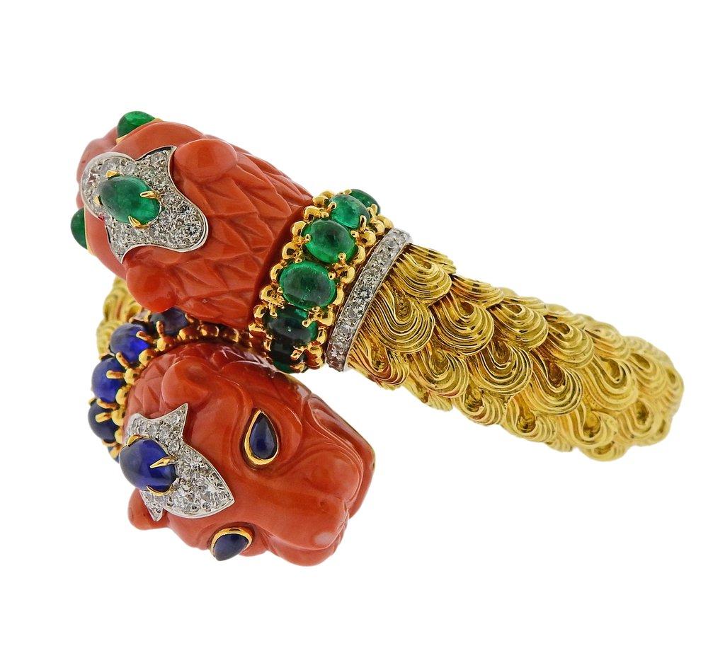 Impressive and iconic twin lion head design bracelet, crafted by David Webb, set in 18k gold and platinum adorned with carved coral, approx. 2.00ctw in H/VS diamonds, sapphires and emeralds. Retail is $165,000. Bracelet will fit approx. 7 - 7.5