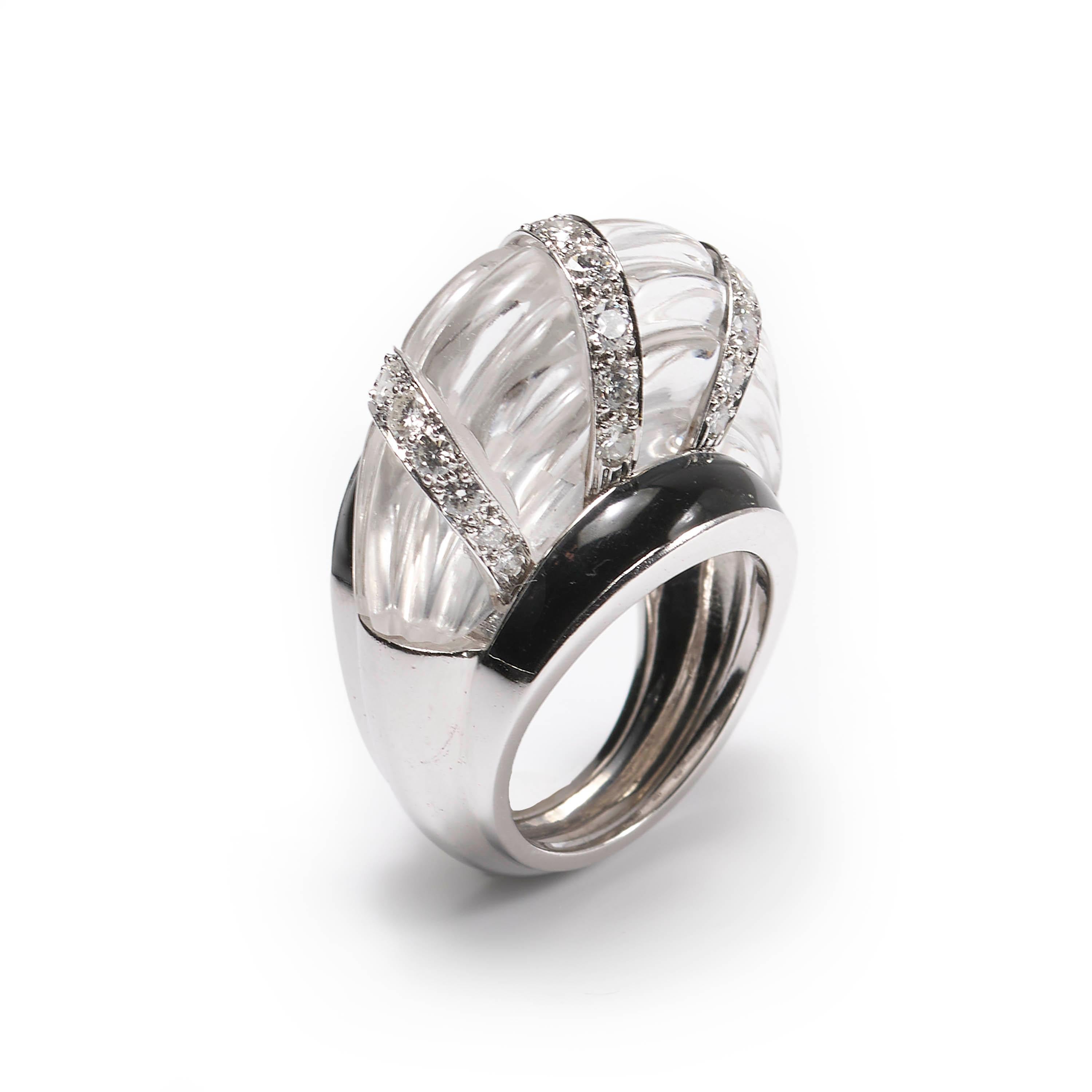A vintage David Webb bombé style ring, comprised of a raised rock crystal centre, carved to create a horizontal, ribbed design, crossed with three columns of round brilliant-cut diamonds set within it, with black enamel bands either side, mounted in
