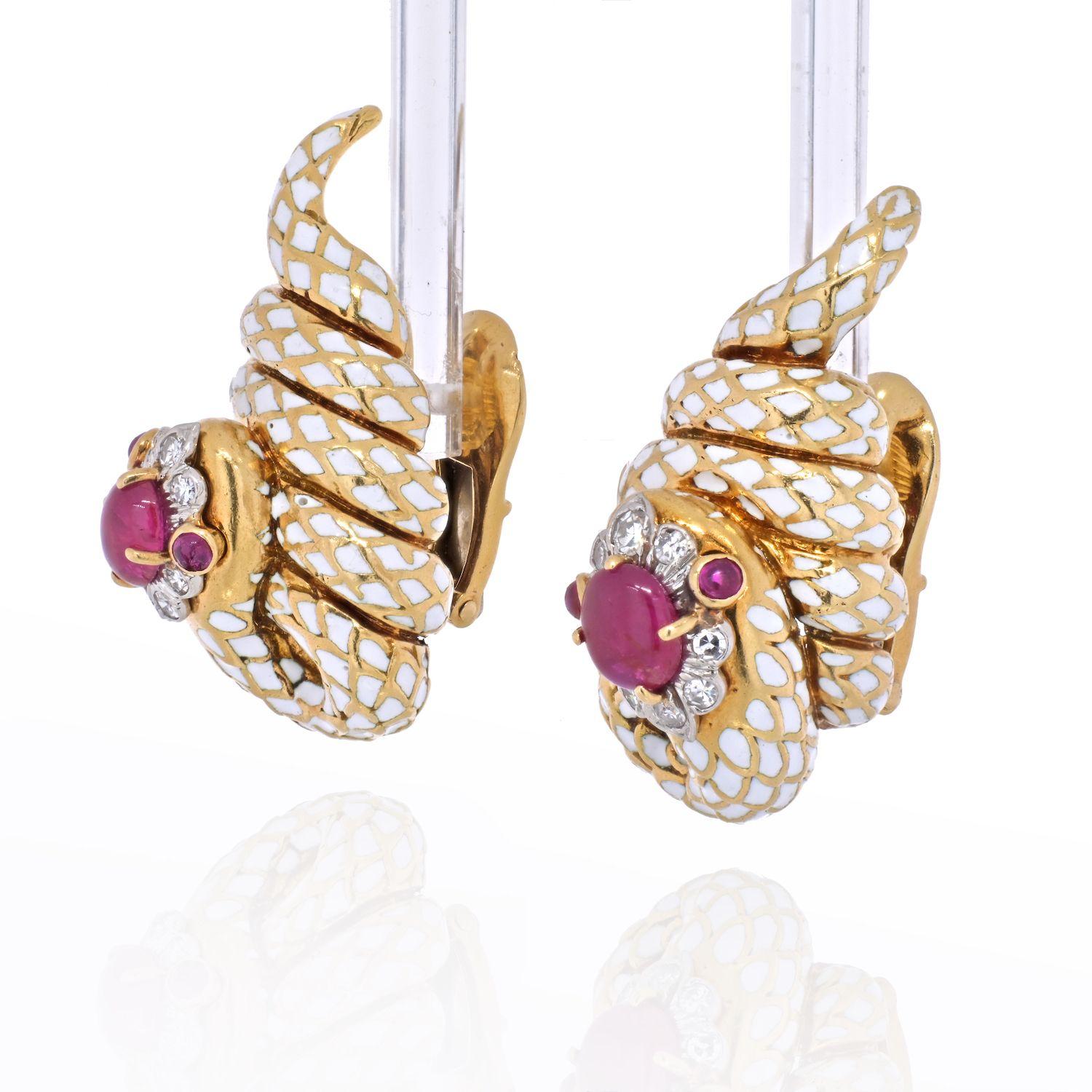 Coiled snake earrings by David Webb. Crafted in 18k yellow gold and platinum. Cabochon rubies, brilliant-cut diamonds, white enamel, 18K gold, and platinum. 
Earring length: 34mm
Earring width: 17mm
Clip on closure. 