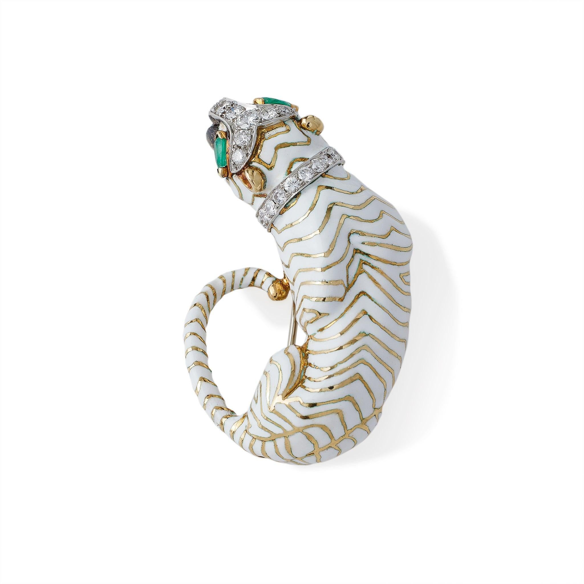 Designed by David Webb in 1965, this 18K gold and white enamel tiger brooch is set with diamonds and emeralds. The 18K gold tiger with white champlevé enamel stripes, pear-shaped cabochon emerald eyes, and round brilliant-cut diamond streak and