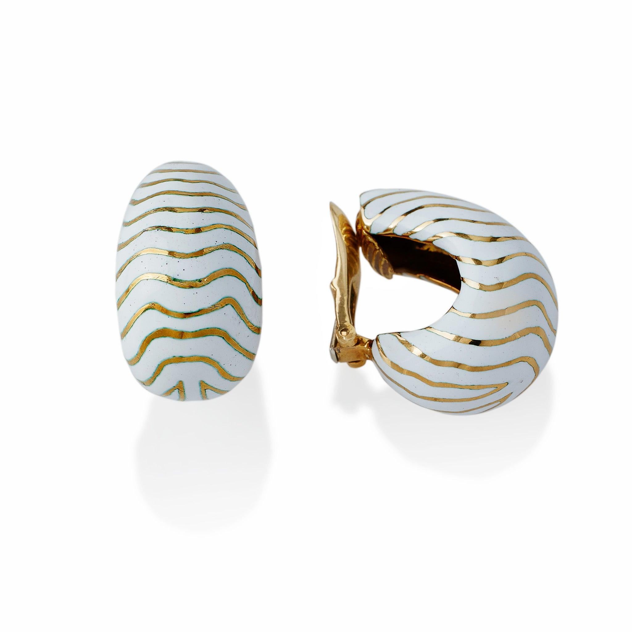 Created in the 1960s-1970s, these tiger half hoop clip earrings are composed of 18K gold and enamel. Each slightly tapered half hoop earring with omega clip back is ornamented with patterned white champlevé enamel stripes. Part of David Webb’s