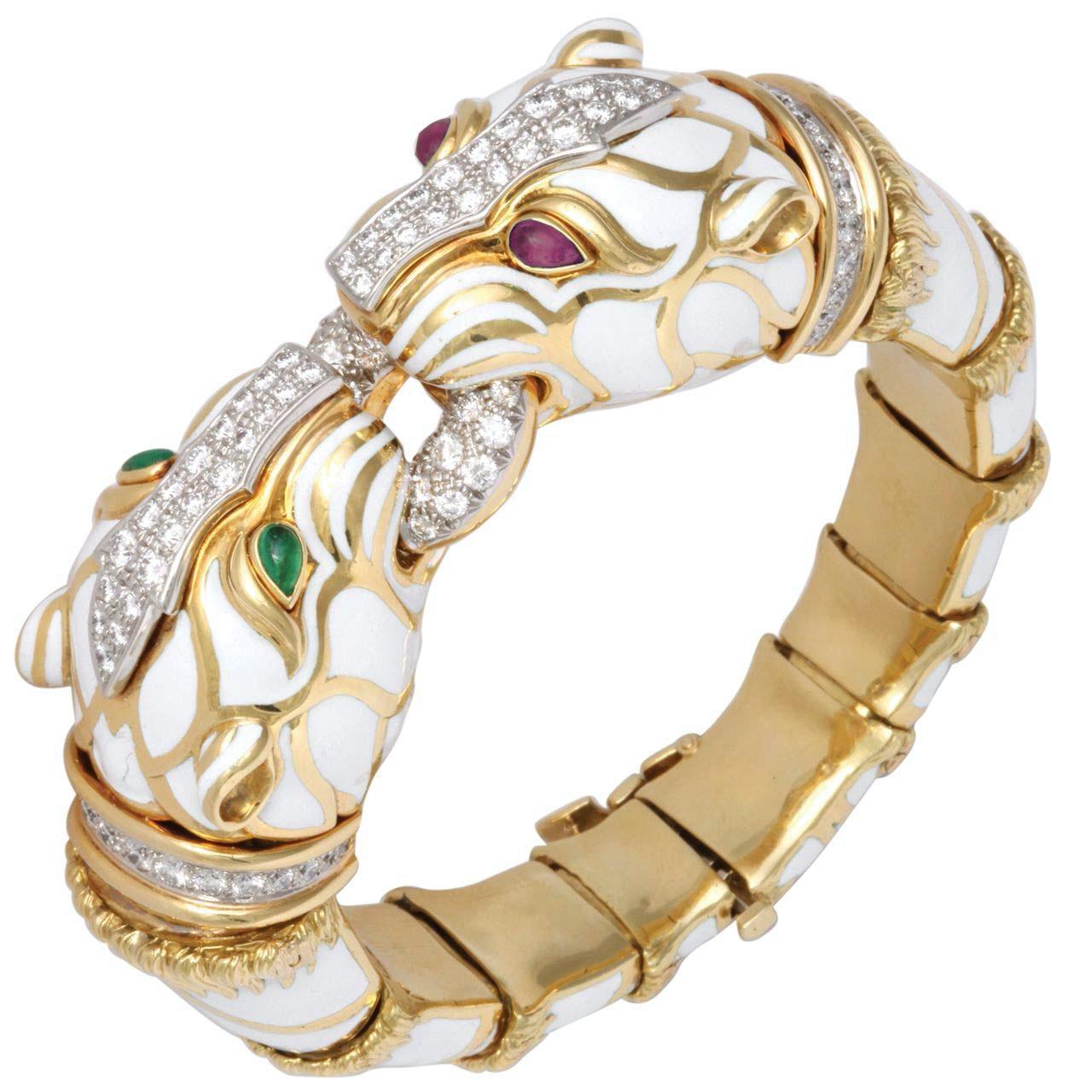 A chic David Webb double tiger bracelet in polished 18kt gold with white enamel, cabochon emeralds and rubies, brilliant-cut diamonds, and platinum. Circa 1970s. Made in the USA.