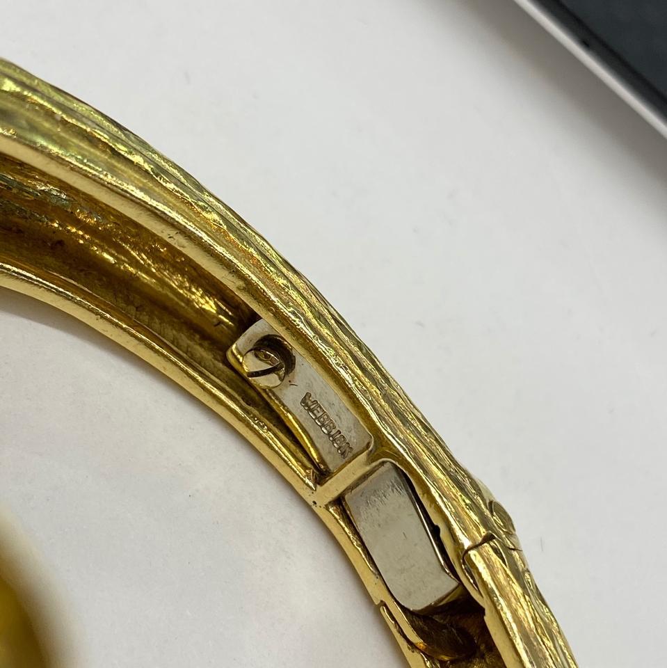 Fluted hammered 18K gold David Webb bracelet.

Gram weight: 82.5
Inside Circumference: 2.2in
Overall width at the widest point: 2 inches.

Luckily this bracelet is not a slip on. It has a hinge mechanism for opening outwards therefore making it easy
