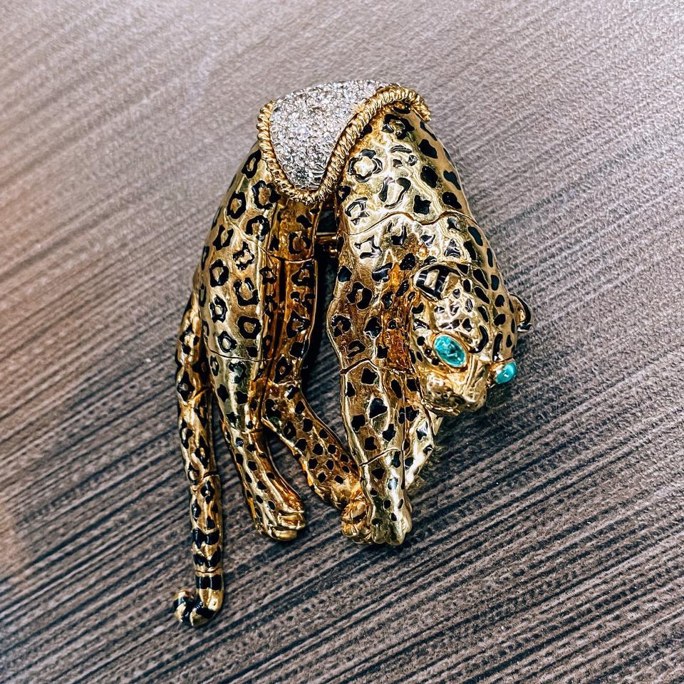 This vintage David Webb brooch features a gorgeous leopard design intricately articulated for realistic movement. The brooch is crafted in 18k yellow gold and accented with cabochon emerald eyes, black enamel spots, and brilliant-cut round diamonds