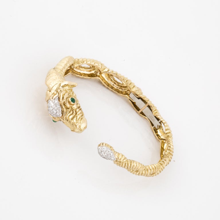 David Webb ram's head bracelet in 18K yellow gold and platinum.  It is a hinged cuff with two cabochon emeralds in the eyes.  In addition, there are eighteen (18) round brilliant-cut diamonds totaling 0.50 carats; G-H color and VS1-2 clarity.  The