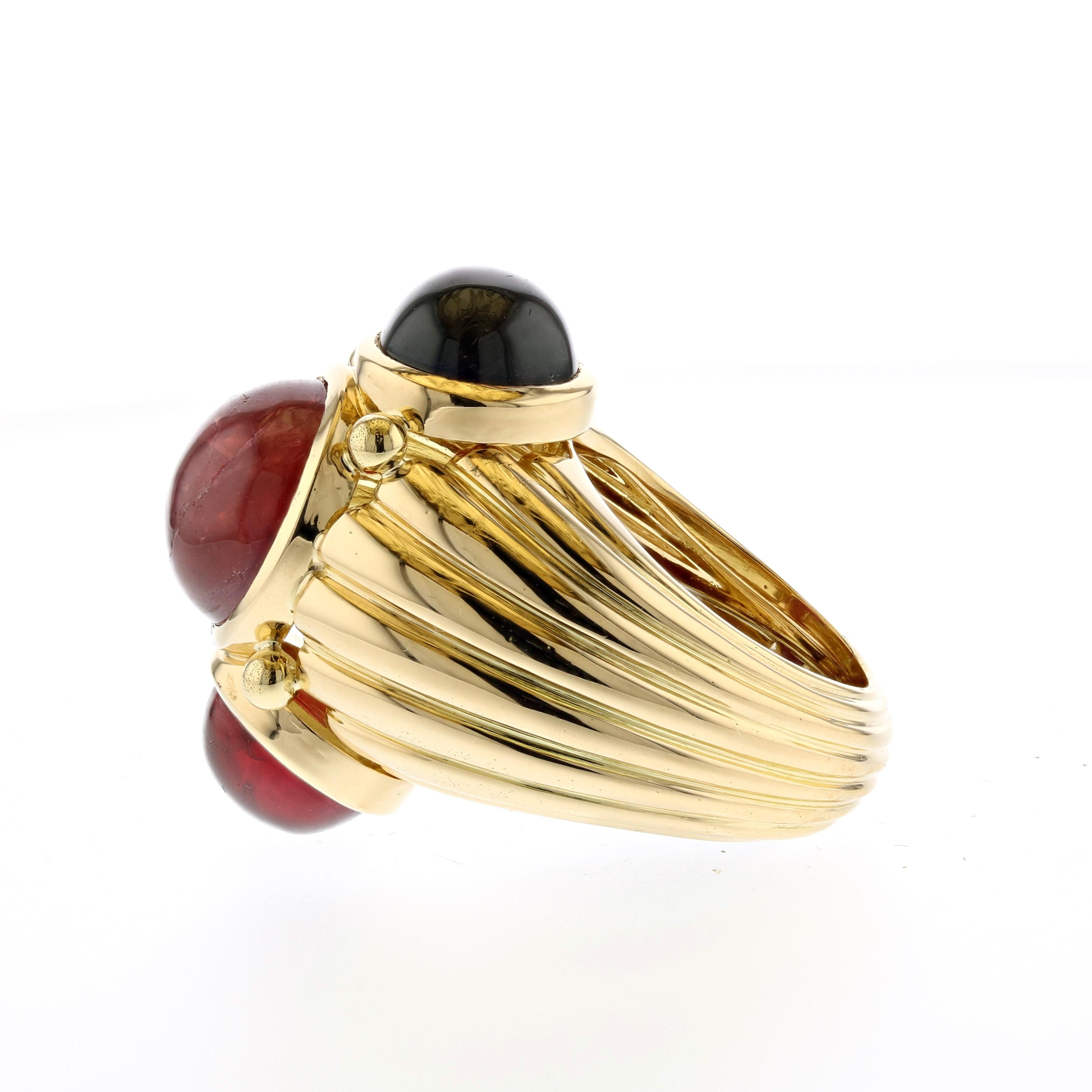 18K yellow gold ring by David Webb.  The center stone is a cabochon ruby weighing 8 carats.  The two cabochon garnets have a combined weight of 10 carats.  Presentation area measures 7/8 of an inch by 1 inch, and stands 5/8 inches off the finger. 