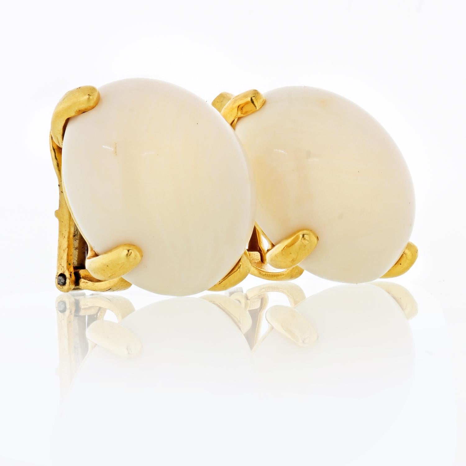 This is a beautiful pair of David Webb earrings in yellow gold with white cabochon cut coral. Simple and beautiful design goes with absolutely every outfit. The smooth surface of the coral has a settle shimmer, the white color has a powderish hue.