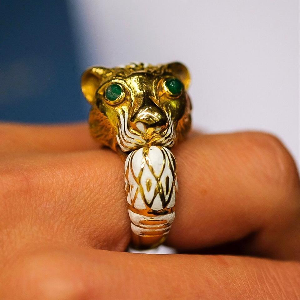 The lion ring features emerald cabochons set in 18k gold, having white enamel accents, marked Webb. Gross weight 24.20 grams.
Size 8. 