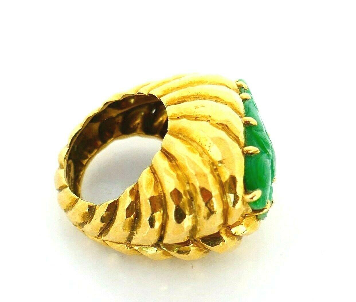 18k yellow hammered gold carved jade ring signed by David Webb, circa 1970s. 
The stone has a delicate leafy design underlining a massive look of the ring.
The ring size is 7. Stamped with the David Webb maker's mark and a hallmark for 18k