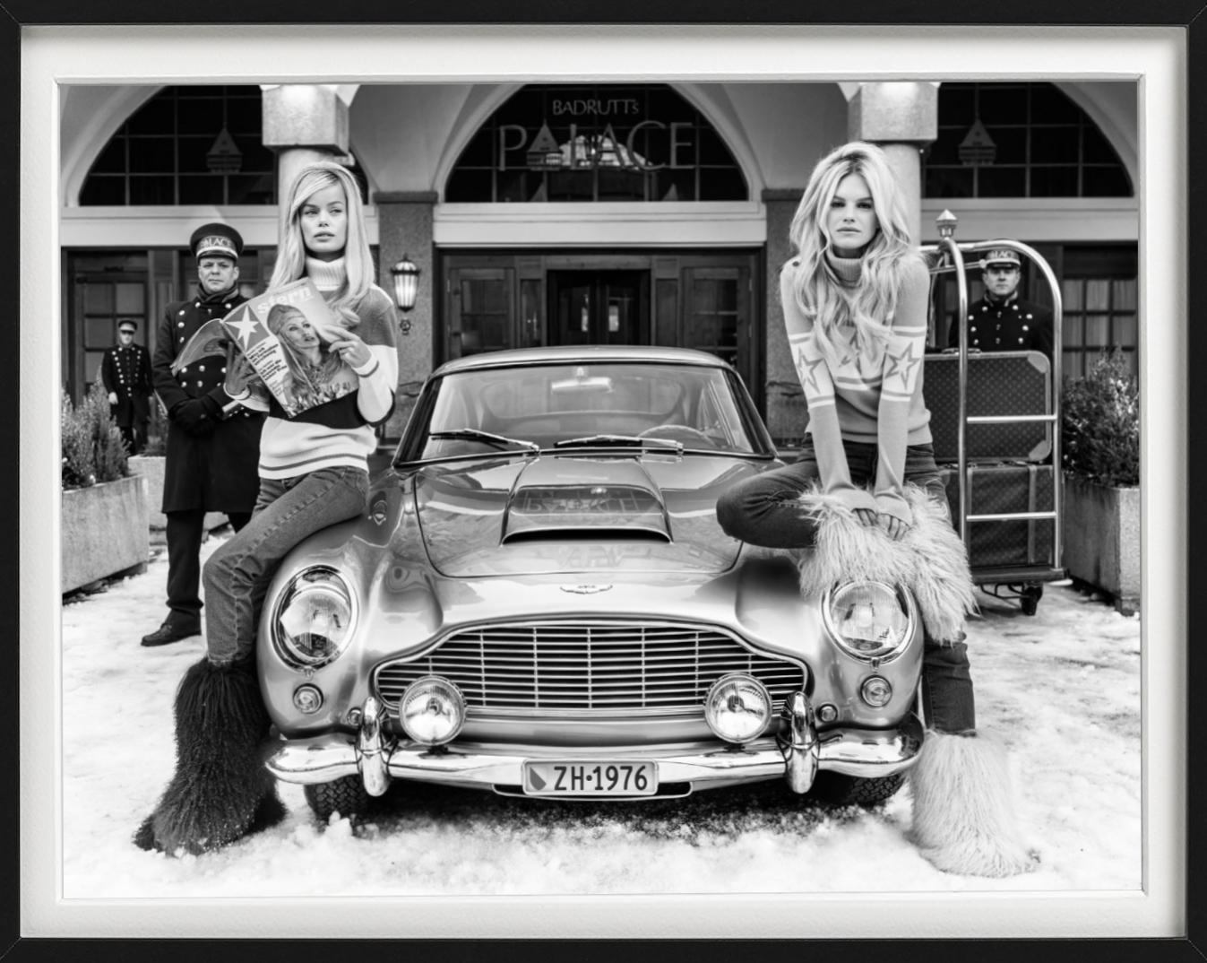 Badrutt's - b&w photograph of two models posing next to a car in St. Moritz  - Photograph by David Yarrow