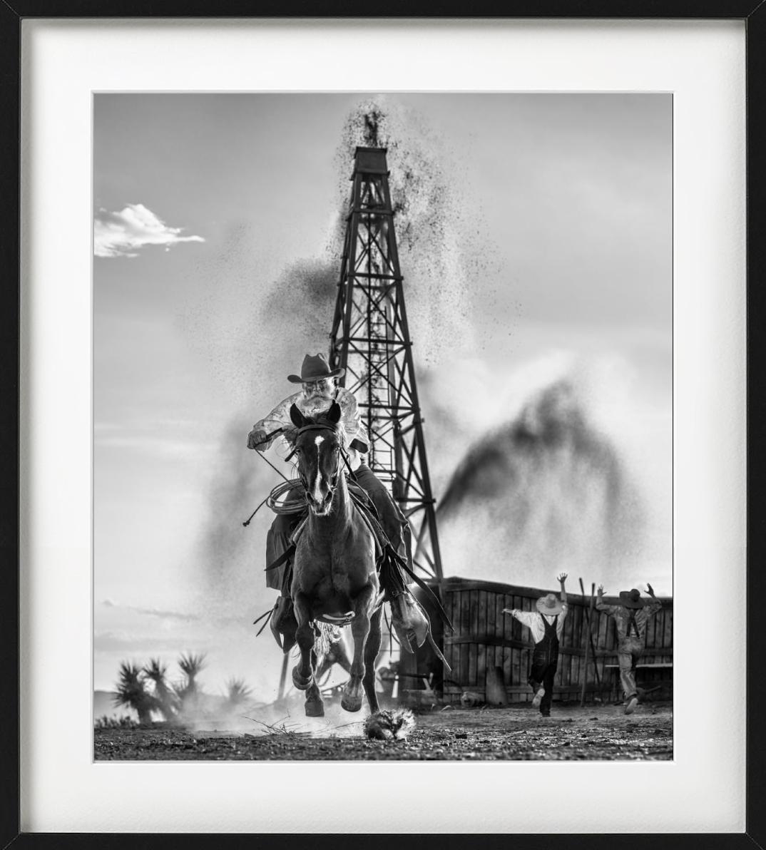 'Black Gold' - Man galopping in front of an oil farm, fine art photography, 2023 - Photograph by David Yarrow
