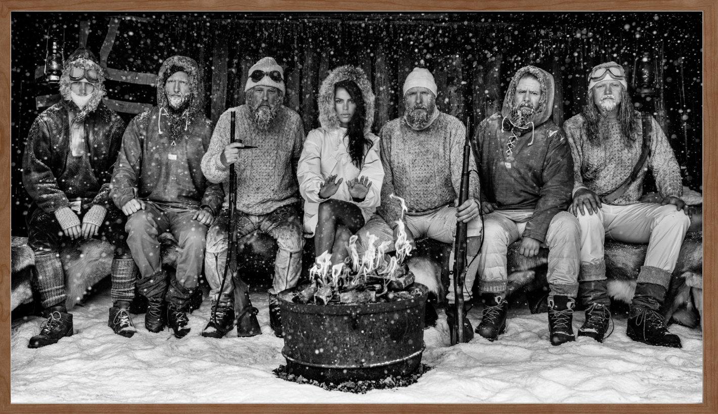 Ice Ice Baby - Model Brooks Nader with Polar Explorers Sitting Around Fireplace - Black Figurative Photograph by David Yarrow
