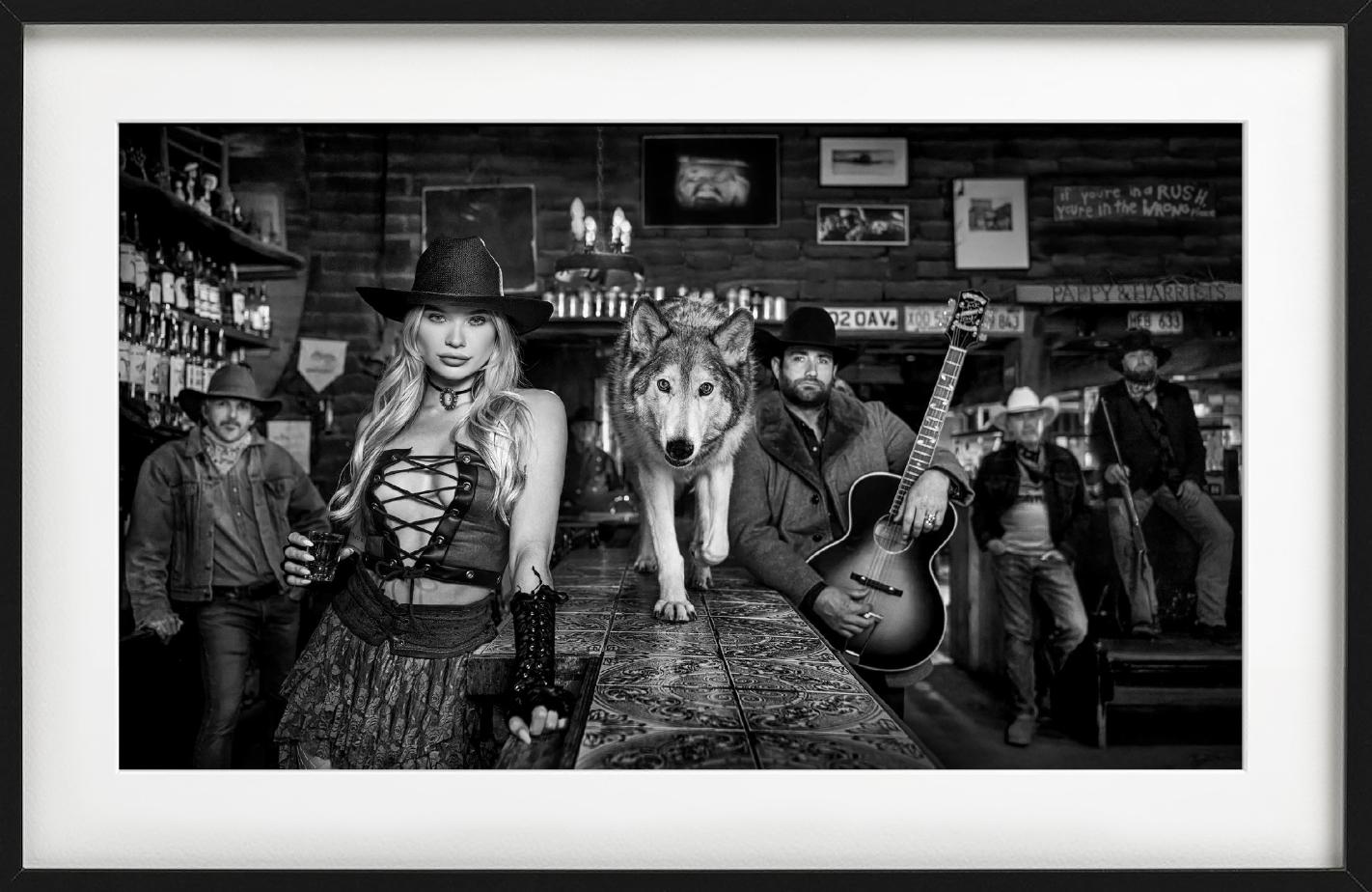 Pappy & Harriet's - Model and Wolf in old Bar, fine art photography, 2024 - Photograph by David Yarrow