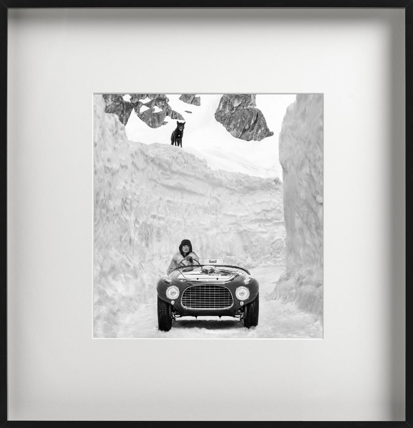 Schwarz-Weiß-Bild eines Oldtimer-Ferraris zwischen hohen Schneewänden, ein schwarzer Wolf schaut von oben zu, fotografiert von David Yarrow im Jahr 2024.

Alle Drucke sind in limitierter Auflage erhältlich. Erhältlich in mehreren Größen. Hochwertige