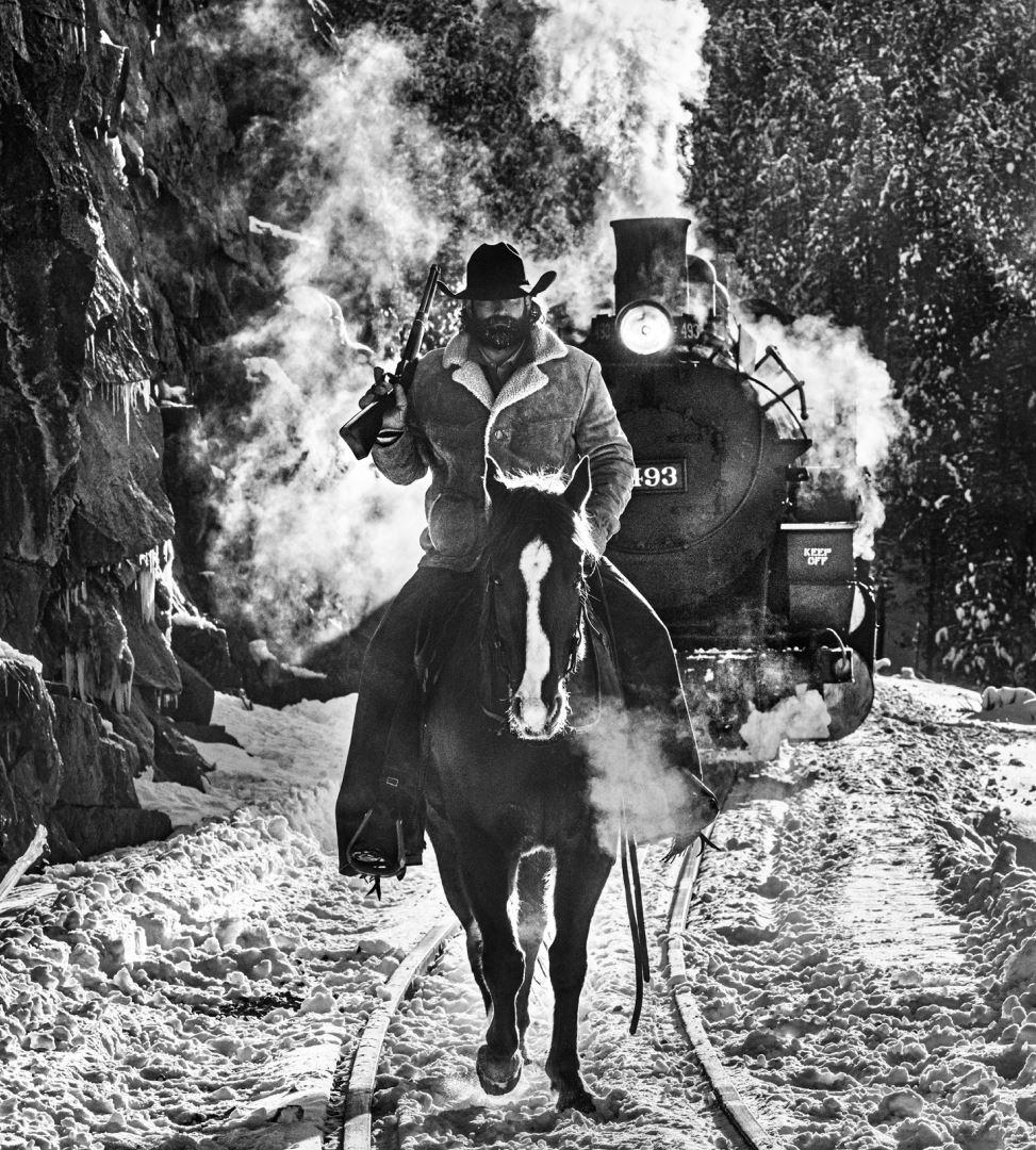 Figurative Photograph David Yarrow - Grim Cowboy Red Dead, cheval chevauchant sur un cheval devant un train à vapeur sauvage