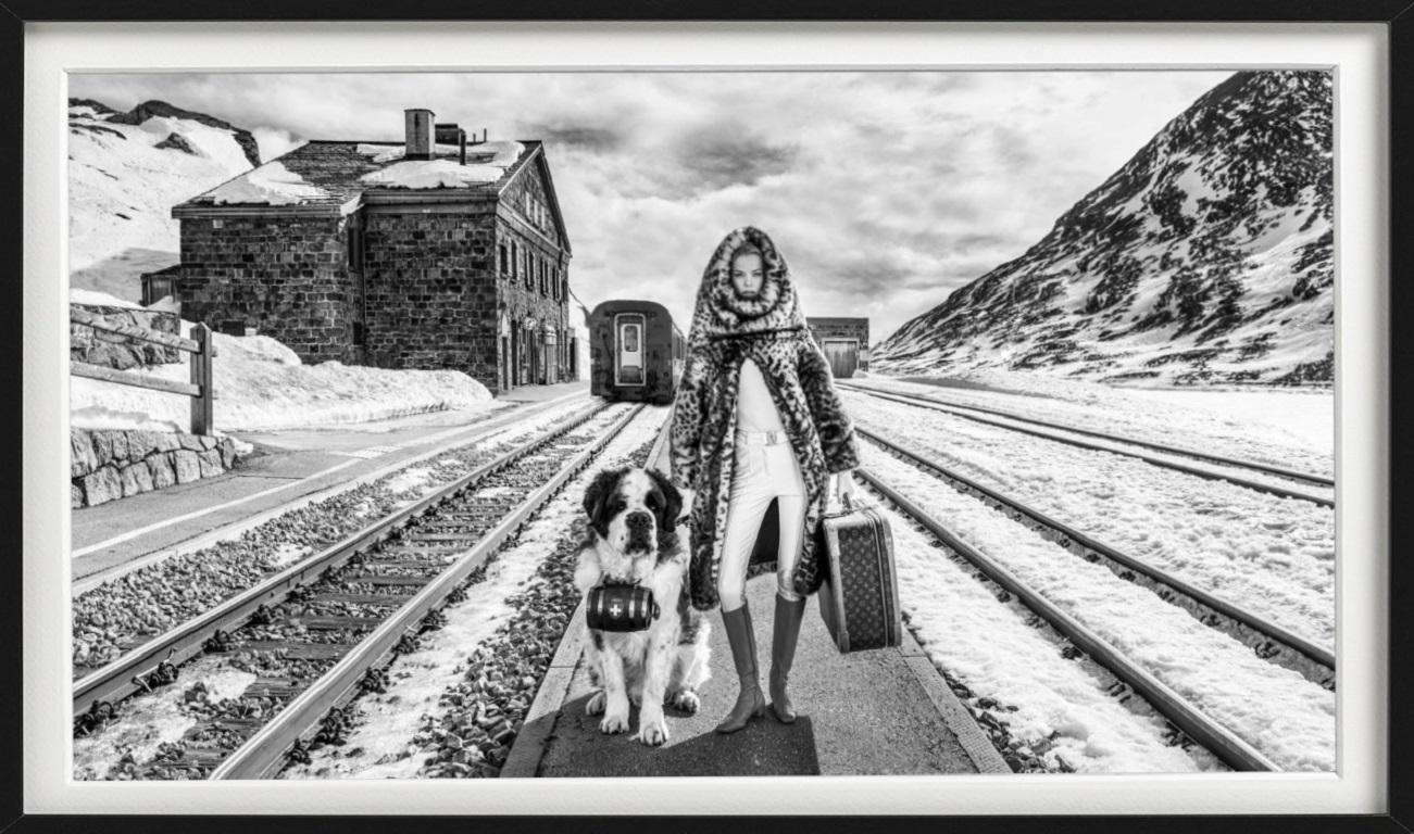 Switzerland - Model and dog standing in front of a train station in the winter - Photograph by David Yarrow