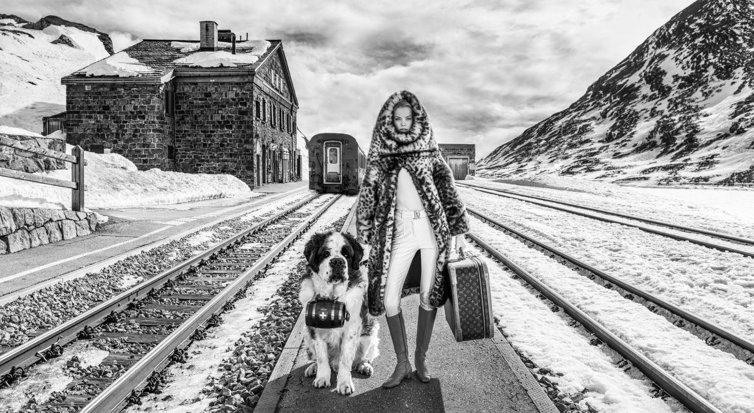 David Yarrow Black and White Photograph - Switzerland - Model and dog standing in front of a train station in the winter