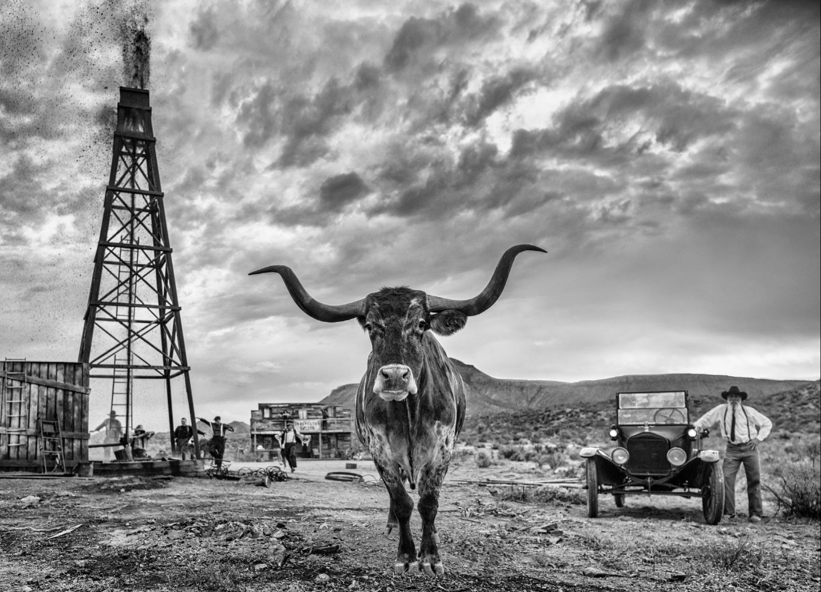 David Yarrow Black and White Photograph - 'Texas' - Cow in front of an old Oil derrick, fine art photography, 2023