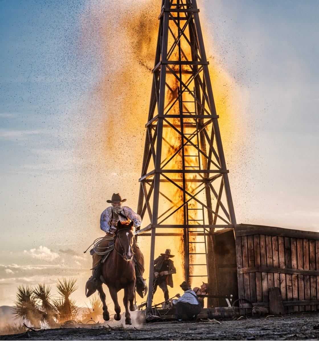 David Yarrow Figurative Photograph - The golden age of Oil - cowboy in front of oil derrick, fine art photography