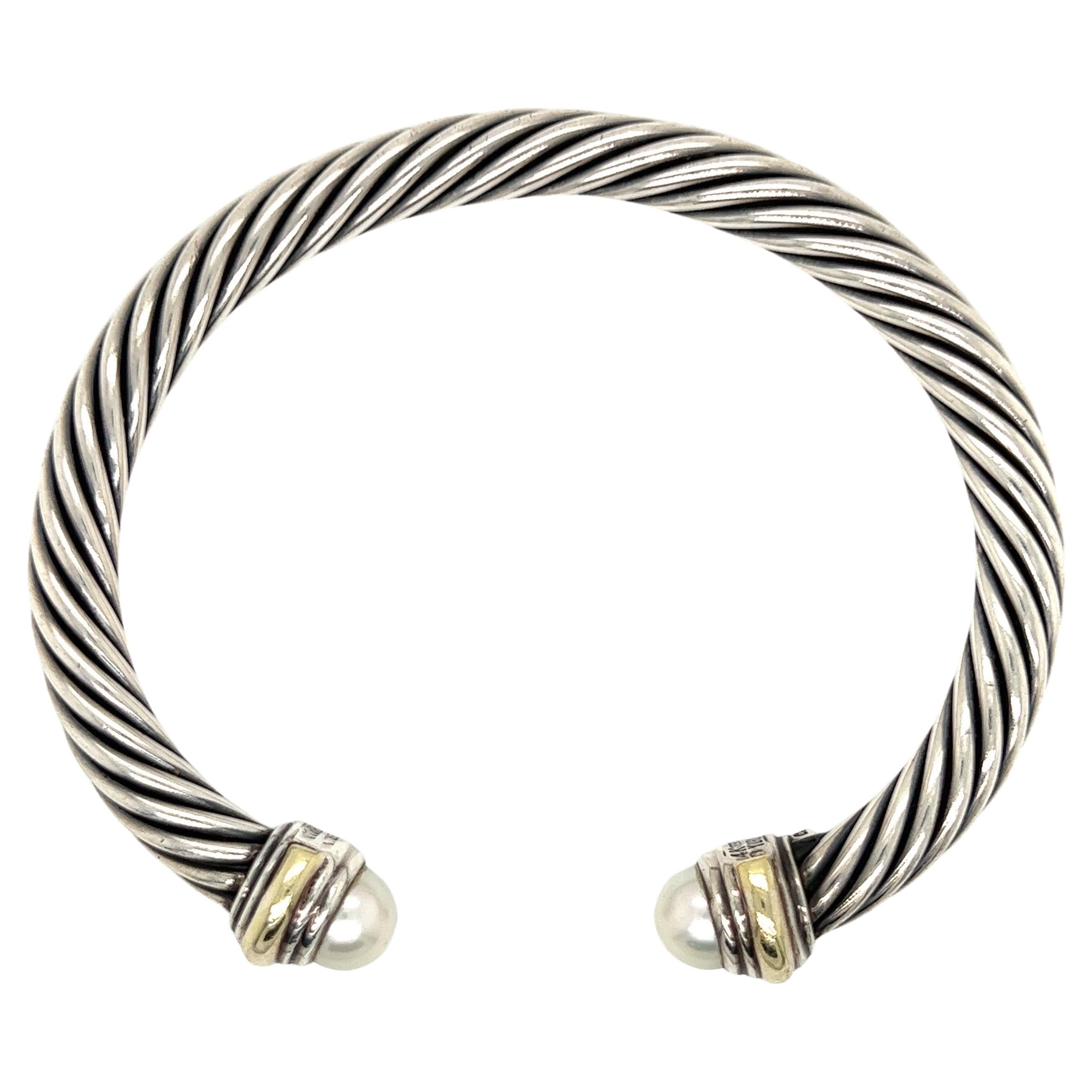 14k Yellow gold with silver cable bangle bracelet.

This David Yurman cable bracelet is composed with both 14k yellow gold as well as silver which complements to the two pearls. This design has evolved over the last 30 years into what it is today.