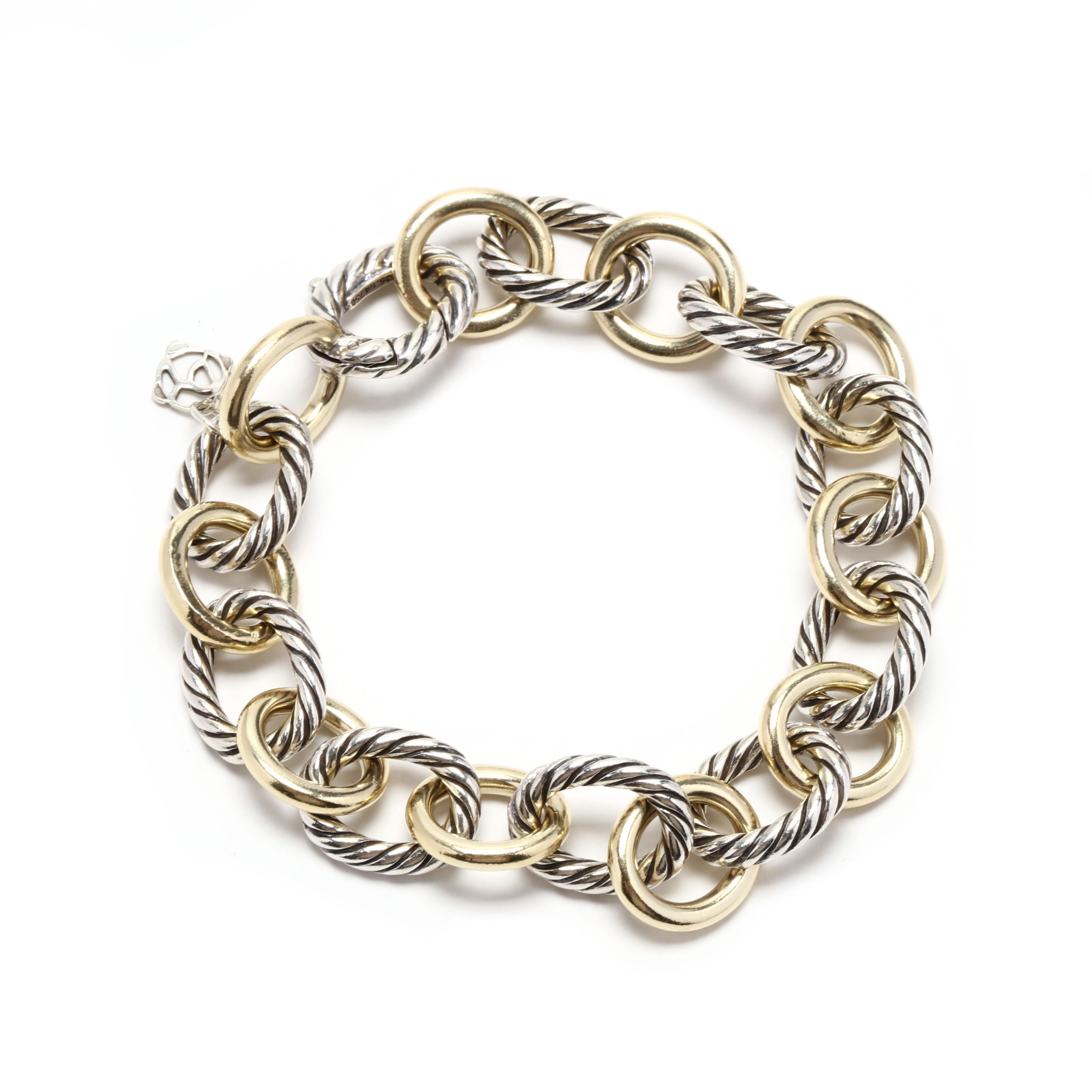 A David Yurman 18 karat yellow gold and sterling silver large cable link bracelet. This bracelet features alternating polished gold oval links with silver oval cable links and with a hidden clasp.



Length: 7.75 in.



Width: 1/2 in., 12