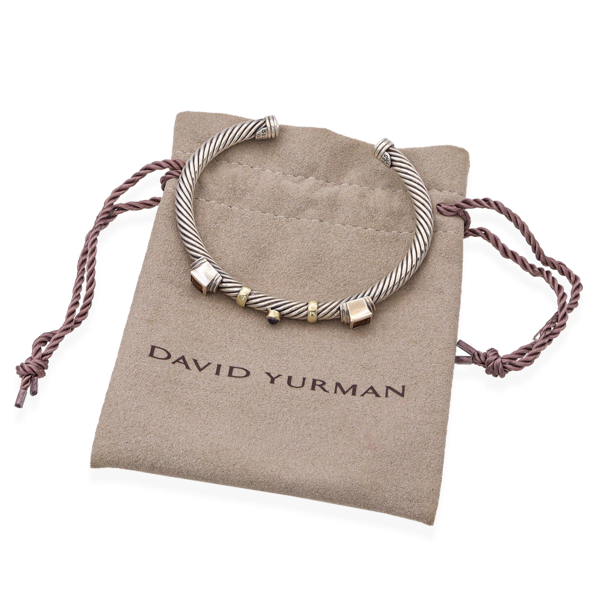 This striking David Yurman cuff bracelet blends the brand’s signature cable design with vibrant gemstones and mixed-metal elegance. Crafted from sterling silver, the twisted cable band is accented with rich 14K yellow gold stations and bezel-set