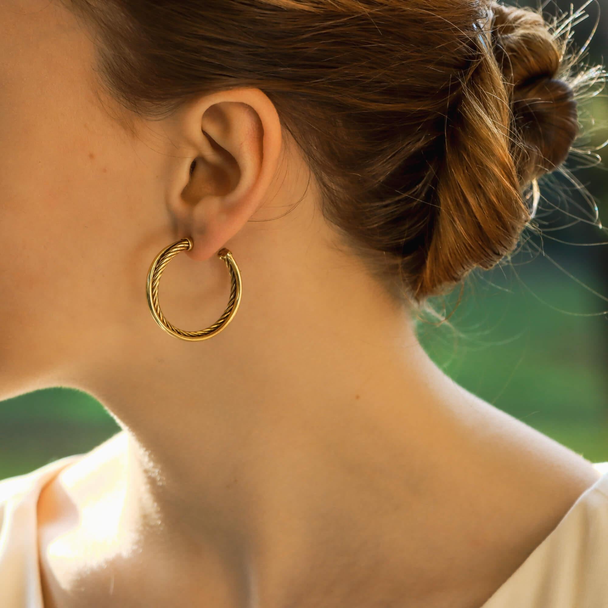 A stylish pair of yellow gold hoop earrings by David Yurman. 
The earrings are formed two entwined gold wires, one with a high polish finish and the other a contrasting rope design. 
The earrings are made of 18 carat yellow gold and have post and