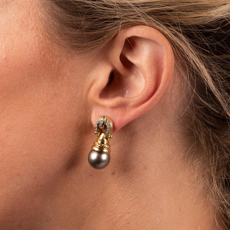 These unique, beautiful earrings feature Tahitian pearl drops set in 18 karat yellow gold with a pave diamond buckle detail. Friction post with butterfly back. 
Measurements: Approximately 1