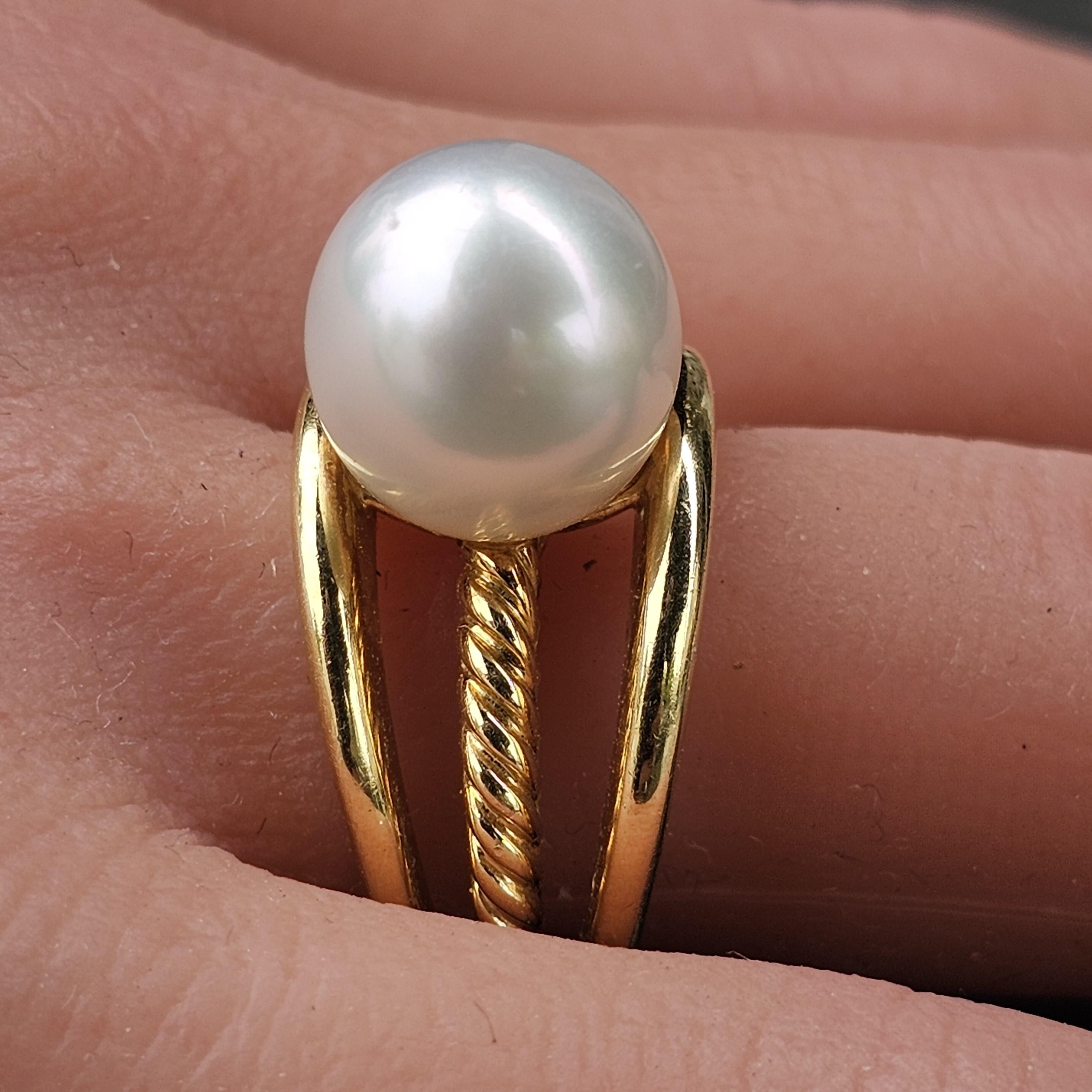 Cette exquise bague David Yurman présente un design captivant centré sur une perle lustrée. Réalisée en or jaune 18 carats, la bague présente un mélange harmonieux de bandes lisses et torsadées, ajoutant profondeur et texture à sa forme élégante. La