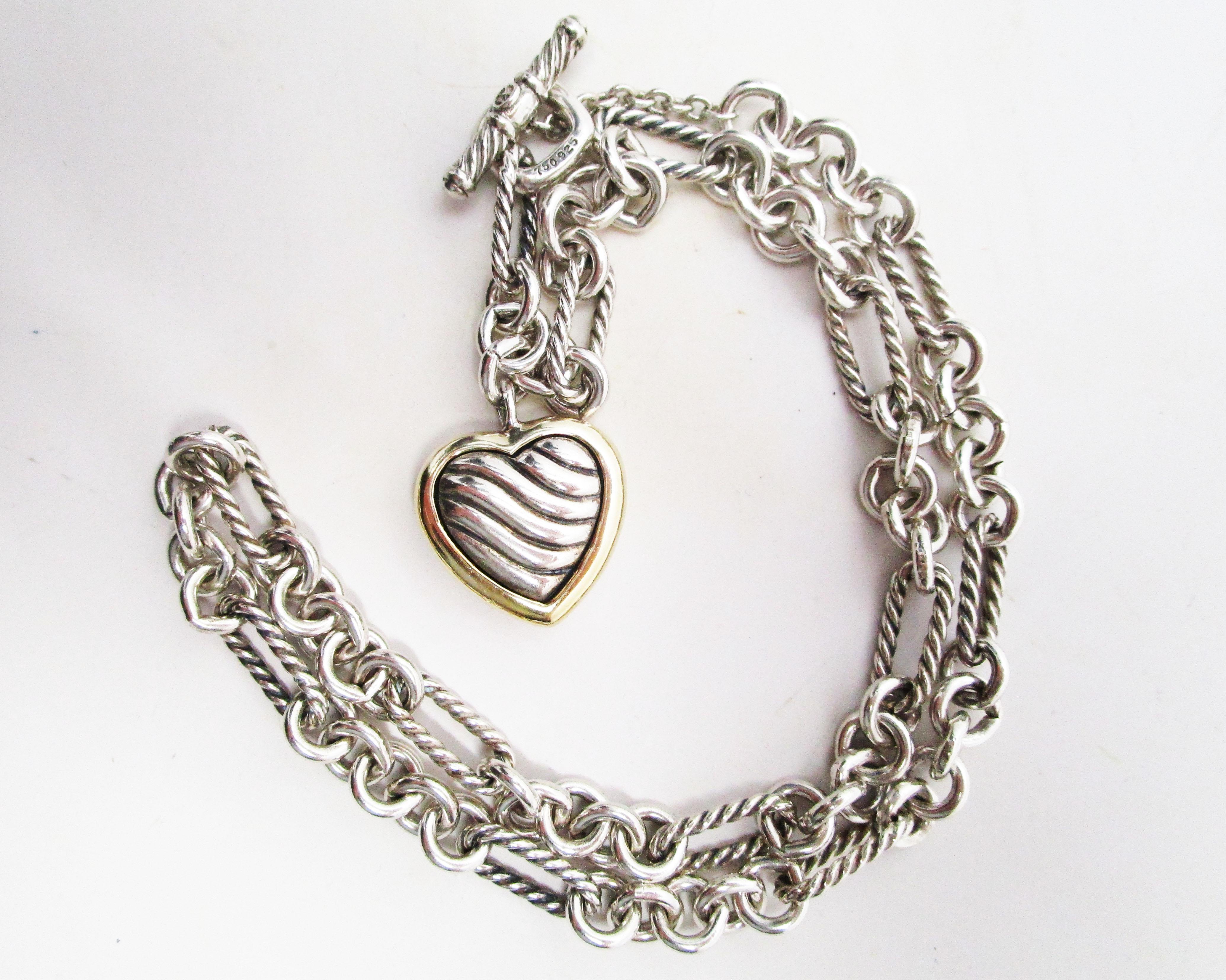 This remarkable David Yurman designer necklace is in 18k yellow gold and sterling silver and features a great chain link design with a fantastic heart pendant! The necklace has a bold link featuring the classic David Yurman twist wire look. The