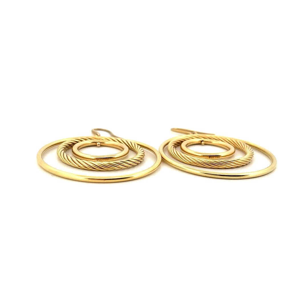 Estos atrevidos pendientes vintage David Yurman de triple aro, elaborados en lujoso oro amarillo de 18 quilates, encarnan el estilo innovador del diseñador de los años 80. Cada pendiente presenta tres aros concéntricos: un círculo interior pulido,