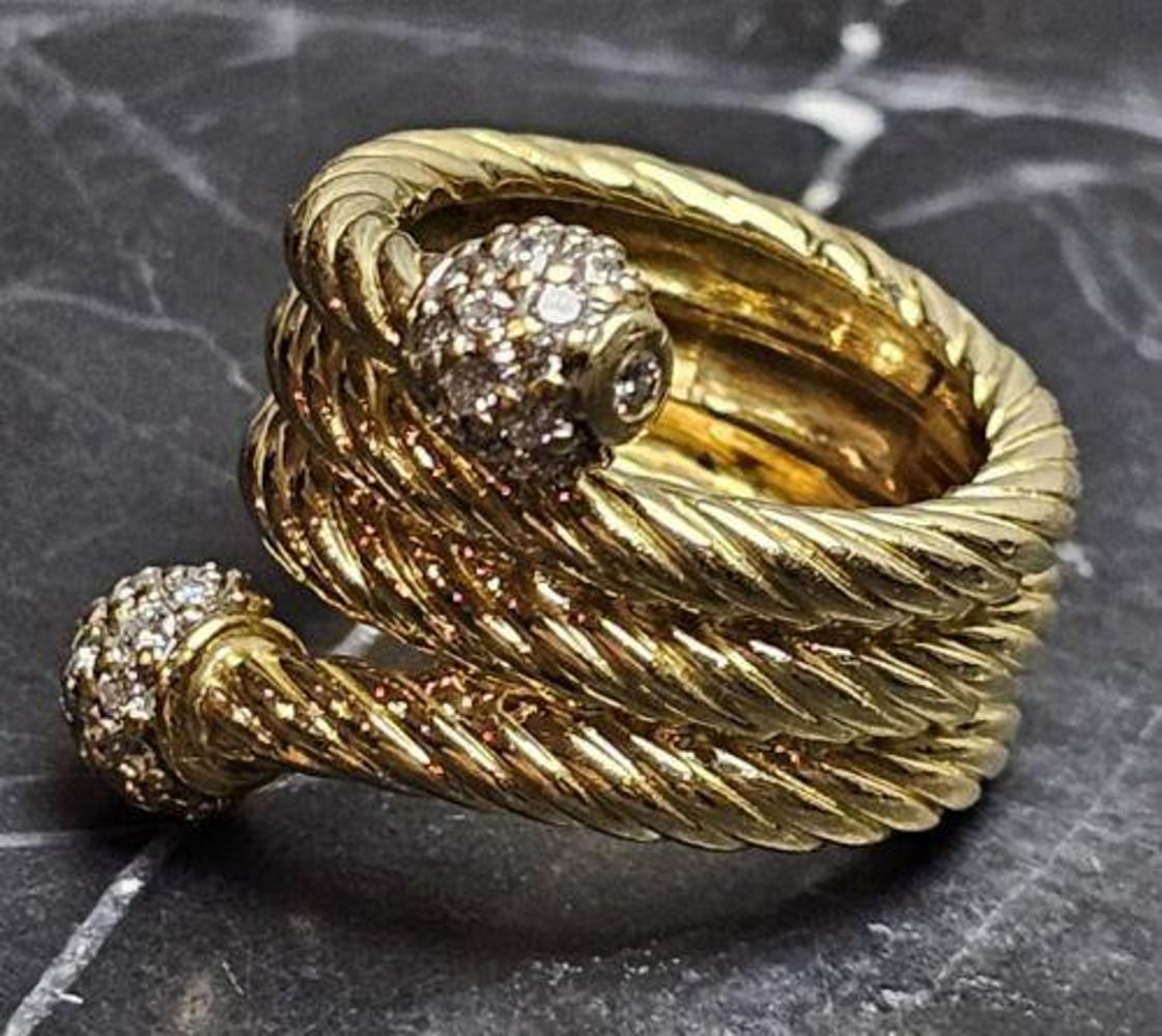 El anillo de diamantes David Yurman 4 Row Cable Bypass está elaborado en oro amarillo de 18 quilates y presenta un diseño único con cuatro filas del icónico motivo de cable de la marca. El anillo está adornado con brillantes diamantes, que añaden un
