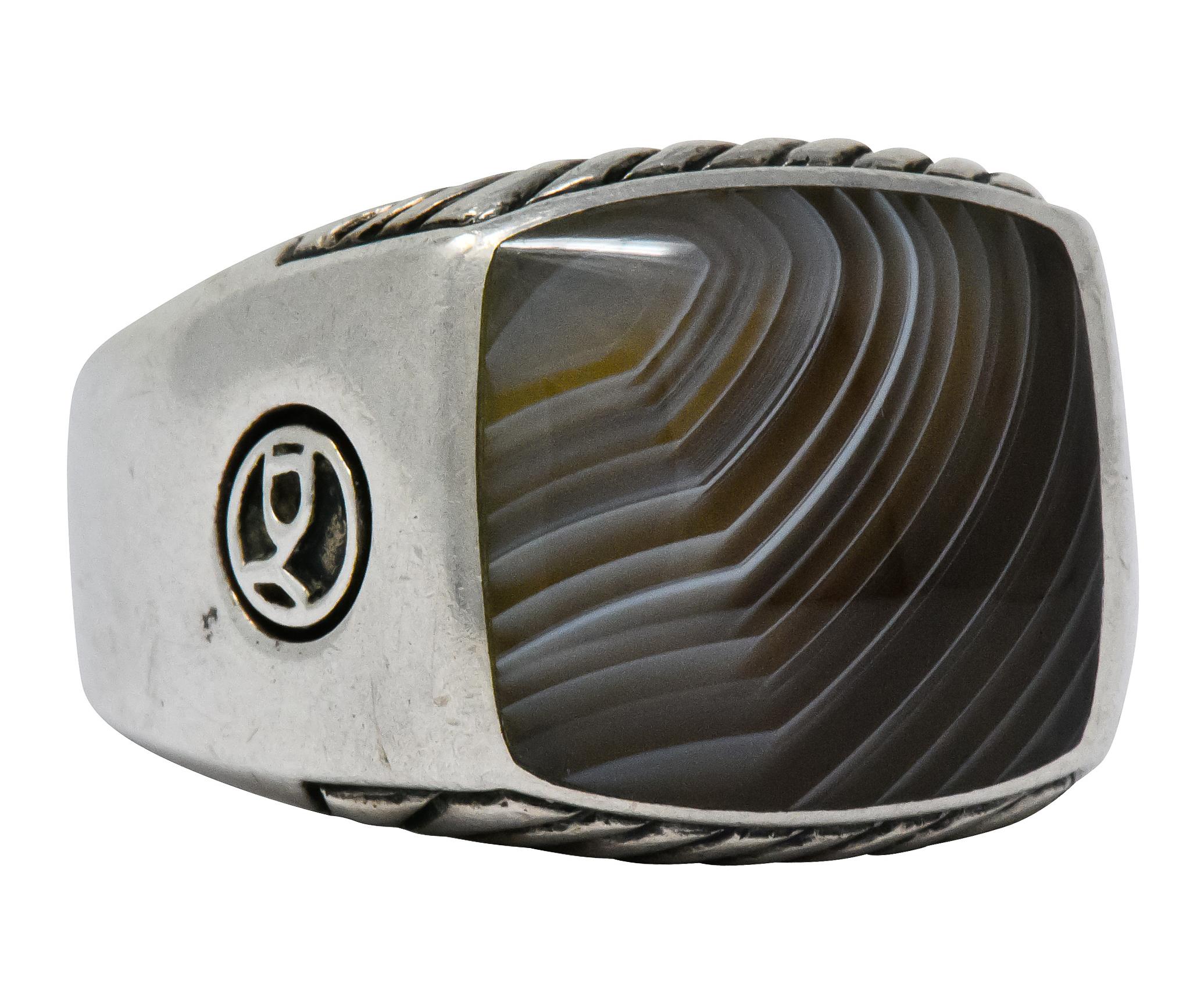 Centering an inlaid square slice of agate, translucent grayish-brown with white banding and excellent polish

Natural agate pattern in concentric rings radiating outward

Accompanied by ribbed silver pattern on profile faces

From David Yurman's