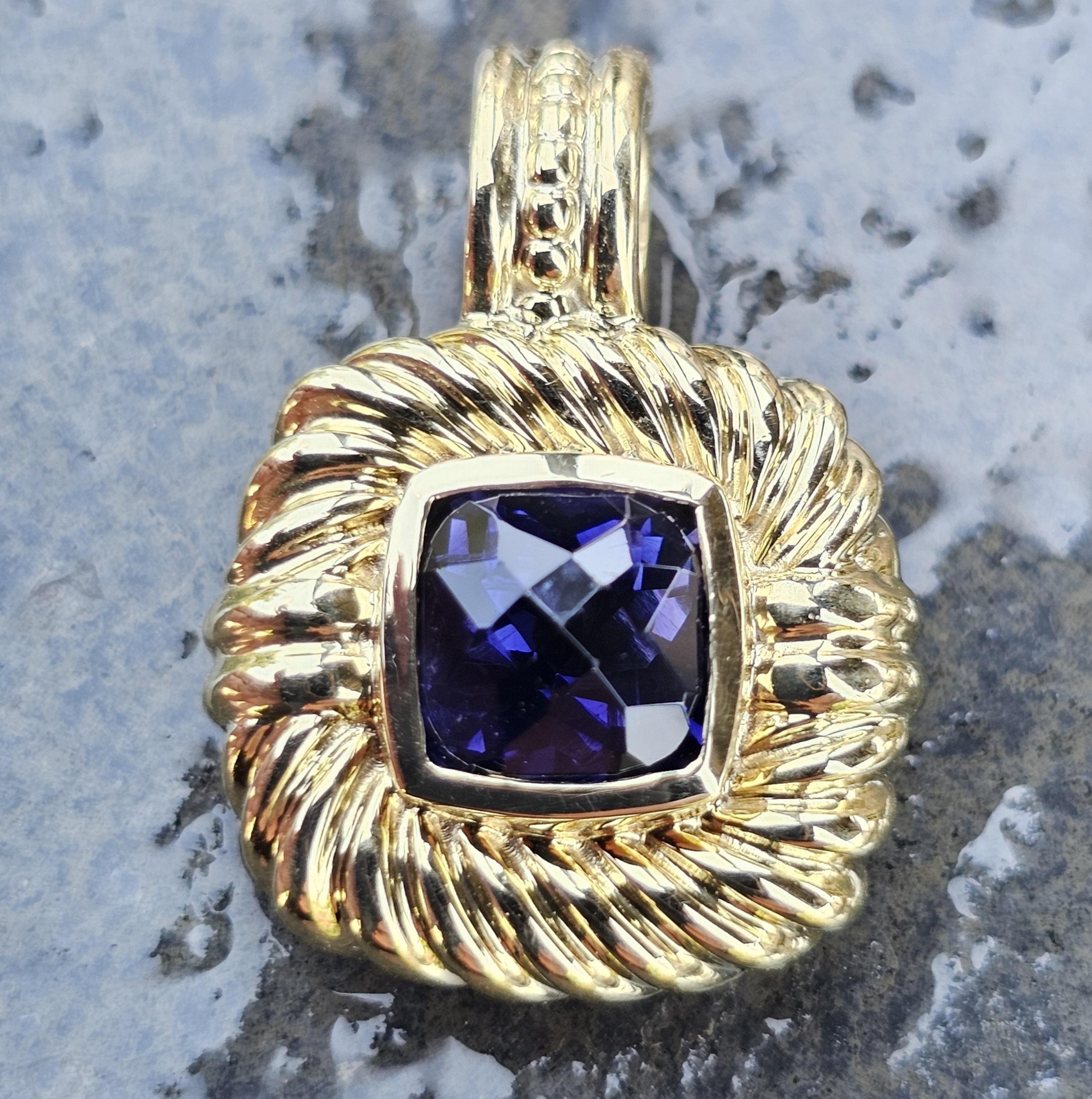 Ce superbe collier à pendentif est un ajout remarquable pour tout amateur de bijoux. Réalisé en or jaune 18 carats, le pendentif met en valeur une iolite centrale taillée en coussin, d'un violet profond. L'élégance du design est accentuée par une