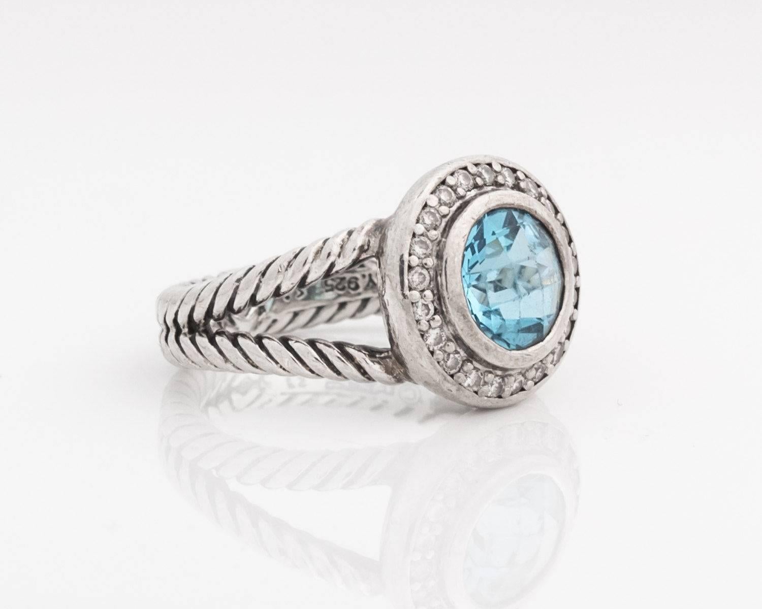 1983 David Yurman Cerise Collection Ring - Sterling Silver, Diamonds, Blue Topaz

This Gorgeous ring features a beautiful round Sky Blue Topaz surrounded by a glittering Diamond Halo. There are 21 diamonds total. All of the gems are bezel set. The