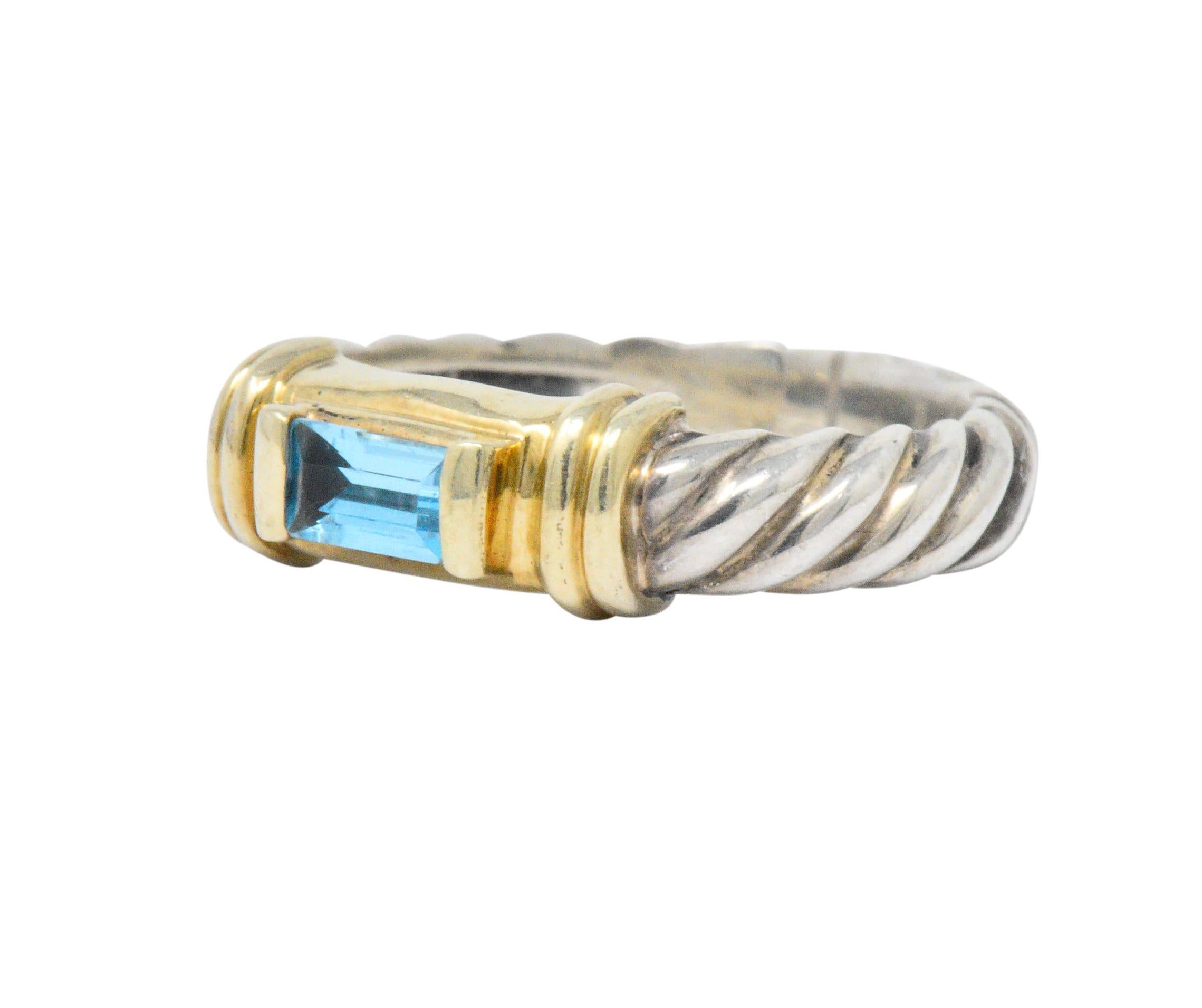 Centering an emerald cut blue topaz, crisp medium blue

Prong set with 14k gold elongated tabs on each end of the stone

14k gold ribbed accents flank stone and sterling silver cable twist band complete the ring

Signed 525 DY 925

Top measures 5 mm