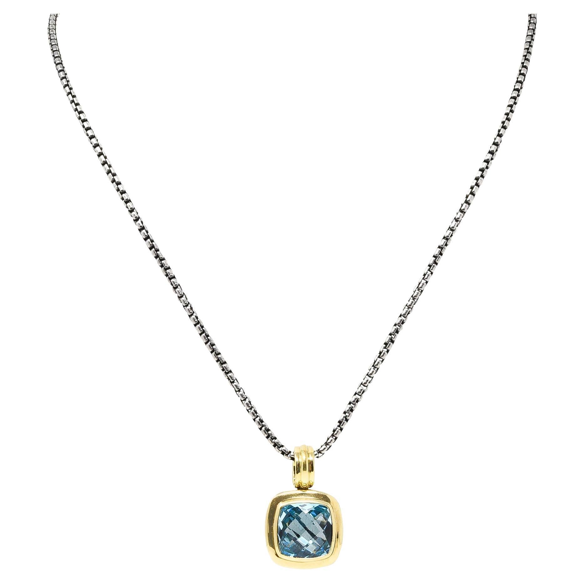 Necklace designed as square enhancer pendant suspended from 2.0 mm box chain 

Centers bezel set mixed cushion cut blue topaz measuring 14.0 x 14.0 mm

Topaz is transparent vibrant blue with high polished gold surround

Accented by silver classic