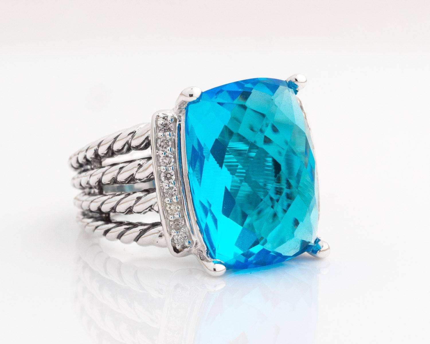 David Yurman Wheaton Ring with Blue Topaz, Diamonds and Sterling Silver

Features a 16 x 12 millimeters Faceted Blue Topaz center stone flanked by one row of Pave Diamonds on each side. The medium blue Topaz is prong set in Sterling Silver. The