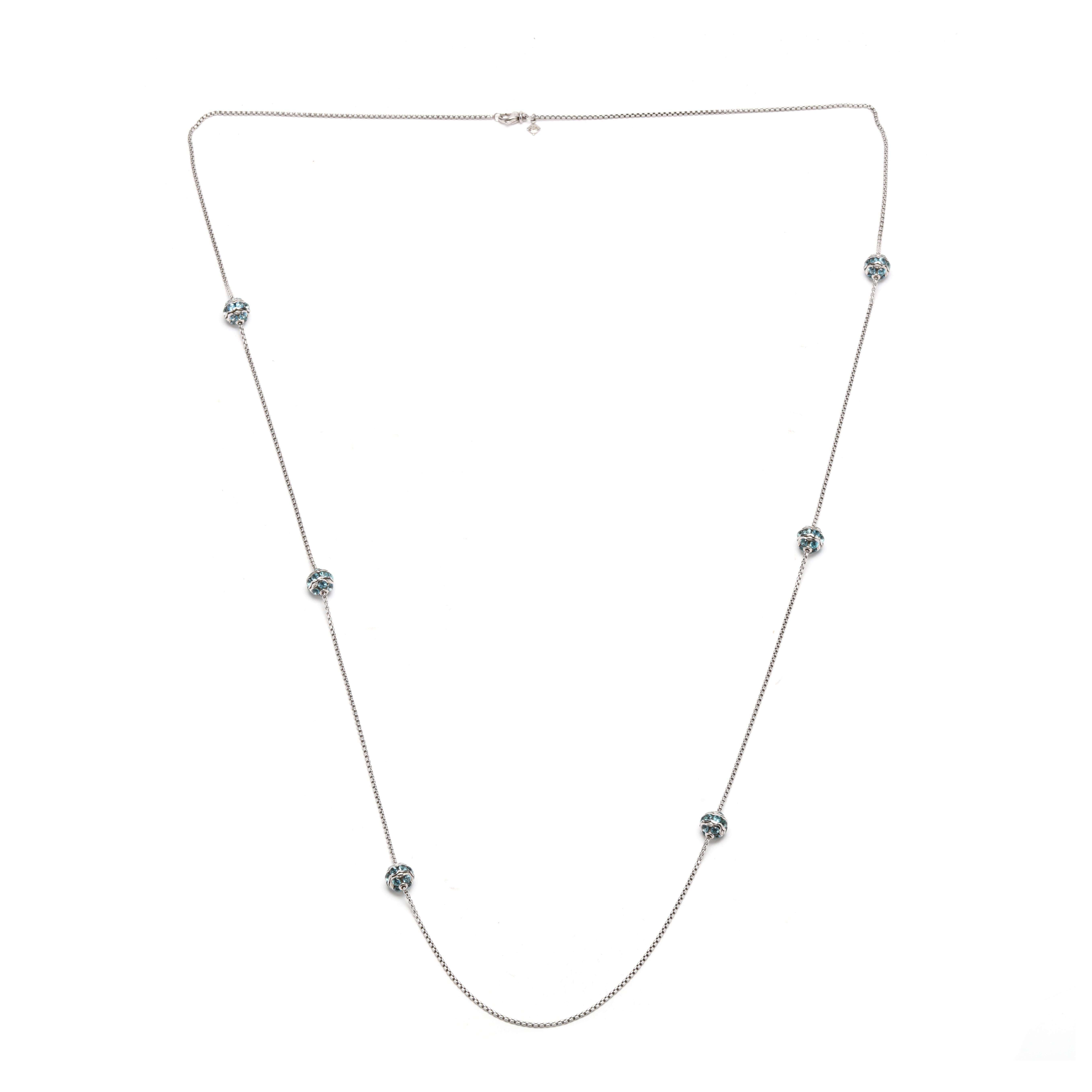 A David Yurman sterling silver and 18 karat yellow gold blue topaz station necklace. This long silver necklace features a thin box chain with six round beads set with round brilliant cut blue topaz stones and with a lobster clasp.

Stones:
- blue