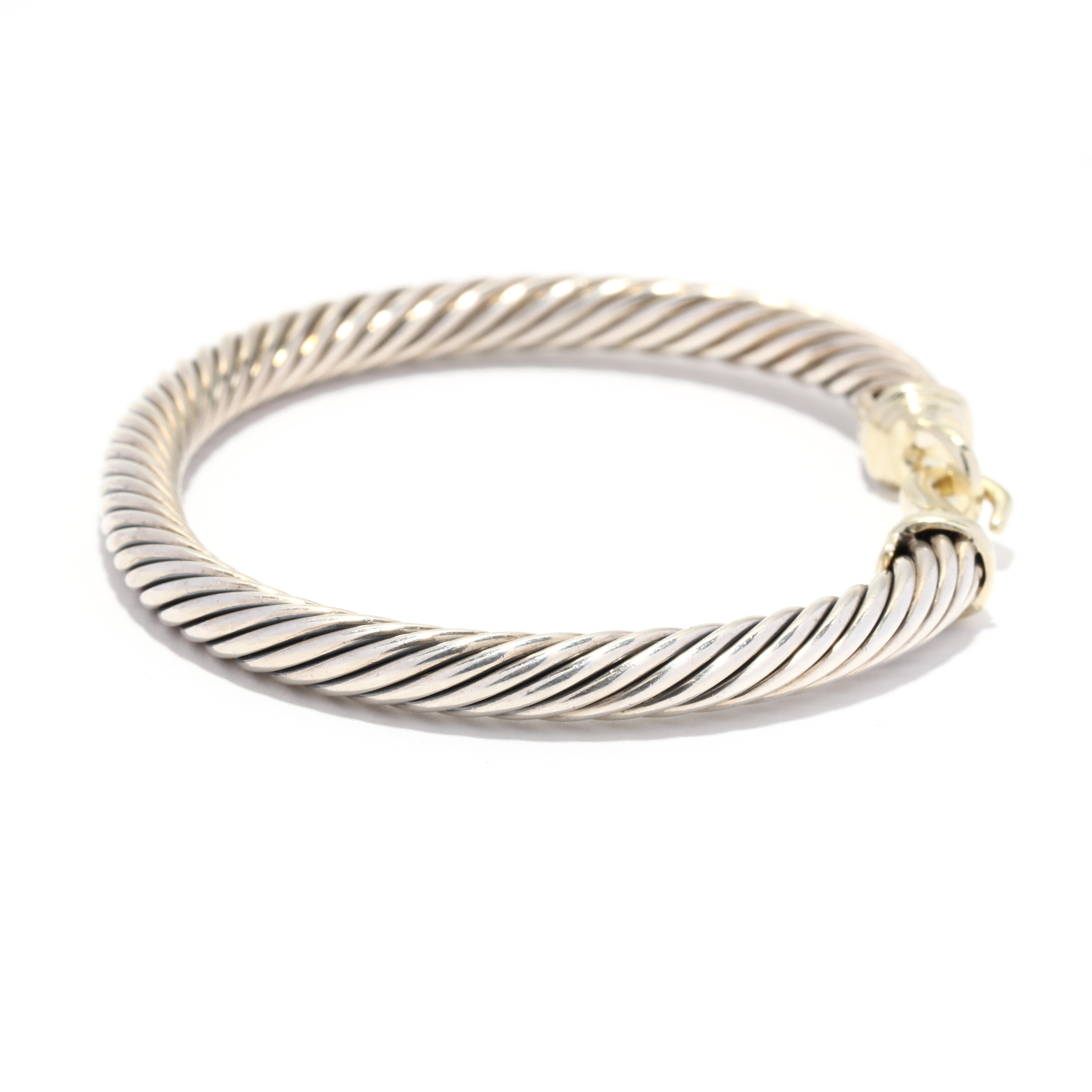 A vintage 14 karat yellow gold and sterling silver buckle cuff bracelet design by David Yurman. This simple bracelet features an adjustable silver cable motif bracelet with a gold hook and eye clasp in a buckle motif.

Length: 6.26 in.

Width: 1/4