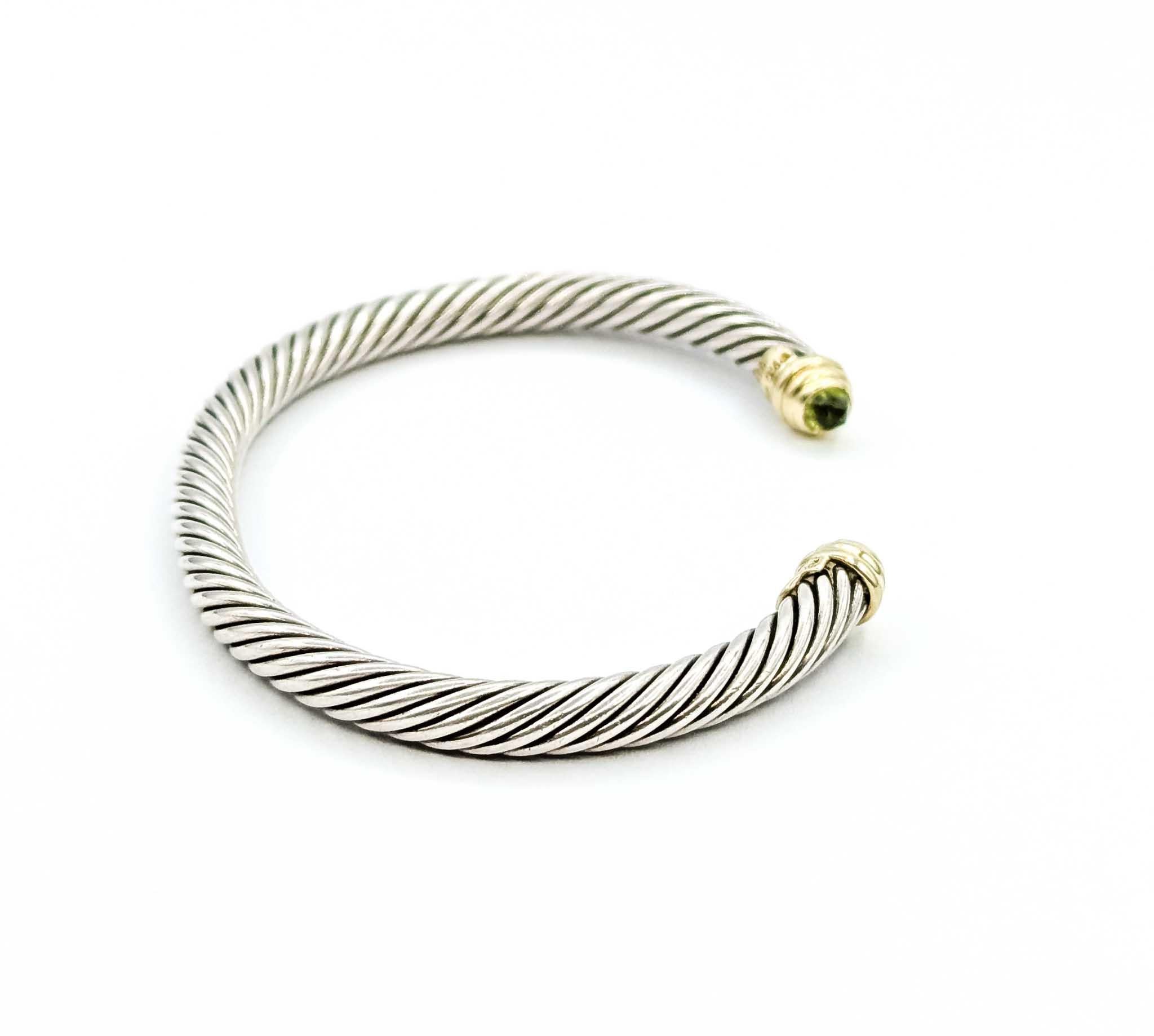 Esta emblemática pulsera cable de David Yurman está elaborada en plata de ley con detalles en oro amarillo de 14 quilates, y pesa unos impresionantes 25,72 gramos. El diseño de cable trenzado, sello distintivo del arte de Yurman, está rematado en