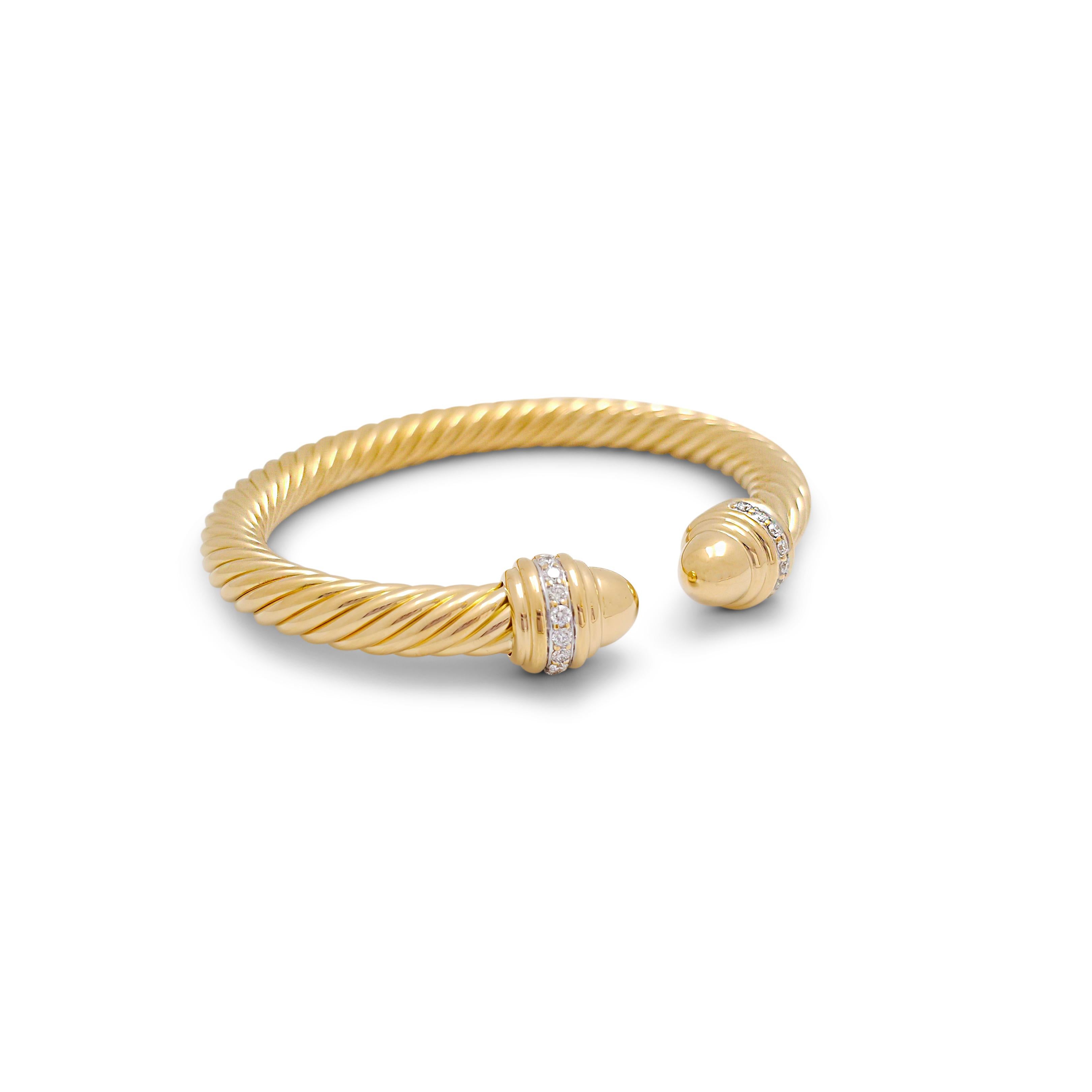 Authentic David Yurman bangle crafted in 18 karat yellow gold. The bracelet is finished with diamond accented domes on either side of the iconic split bangle for an estimated total weight of 0.41 carats. The bangle is a size medium and fits up to a