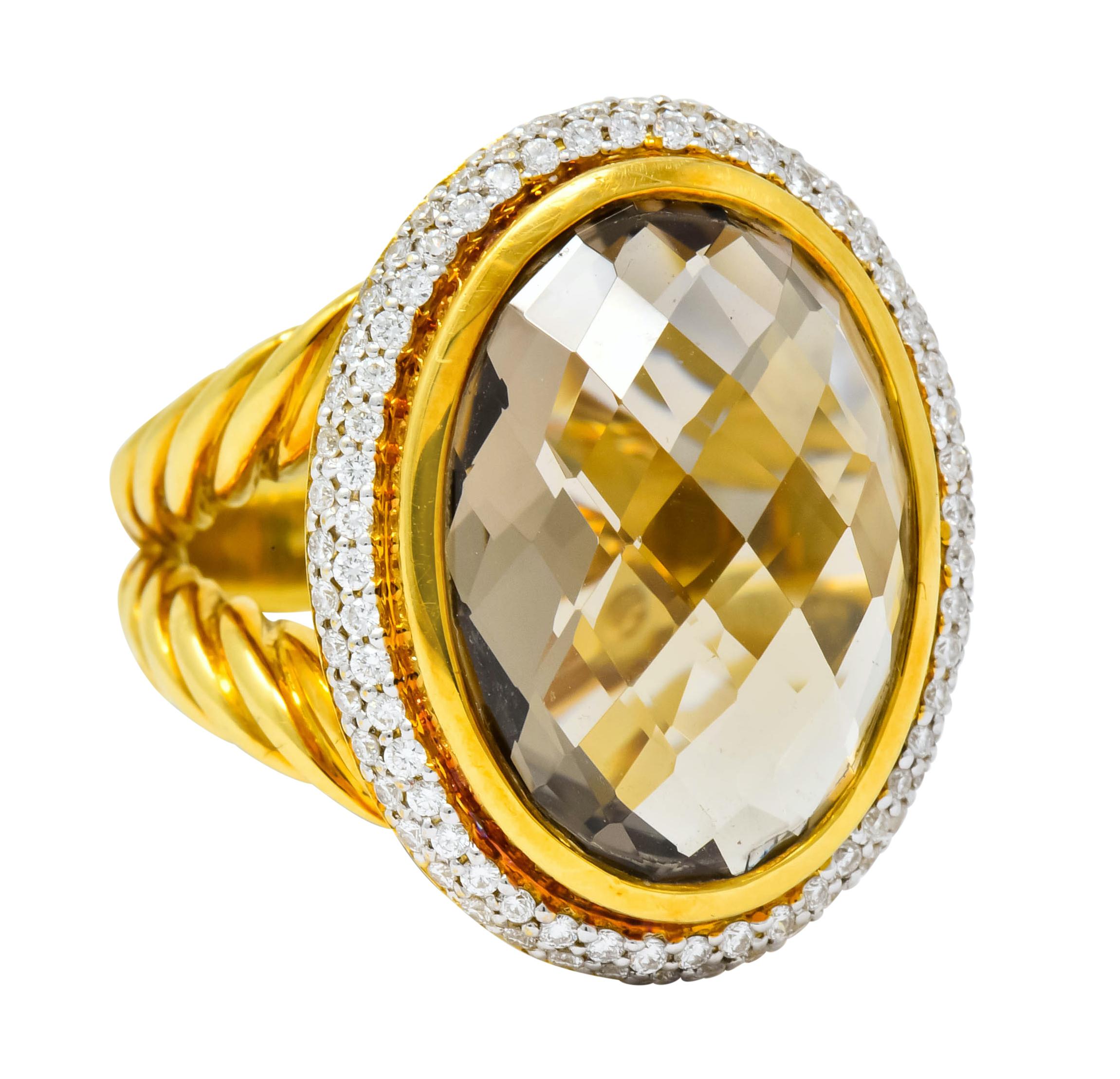 Centering an oval checkerboard cut topaz measuring approximately 18.0 x 13.0 mm, transparent and very light golden color

Bezel set in a polished gold surround with halo of pavé set round brilliant cut diamonds weighing approximately 1.00 carat