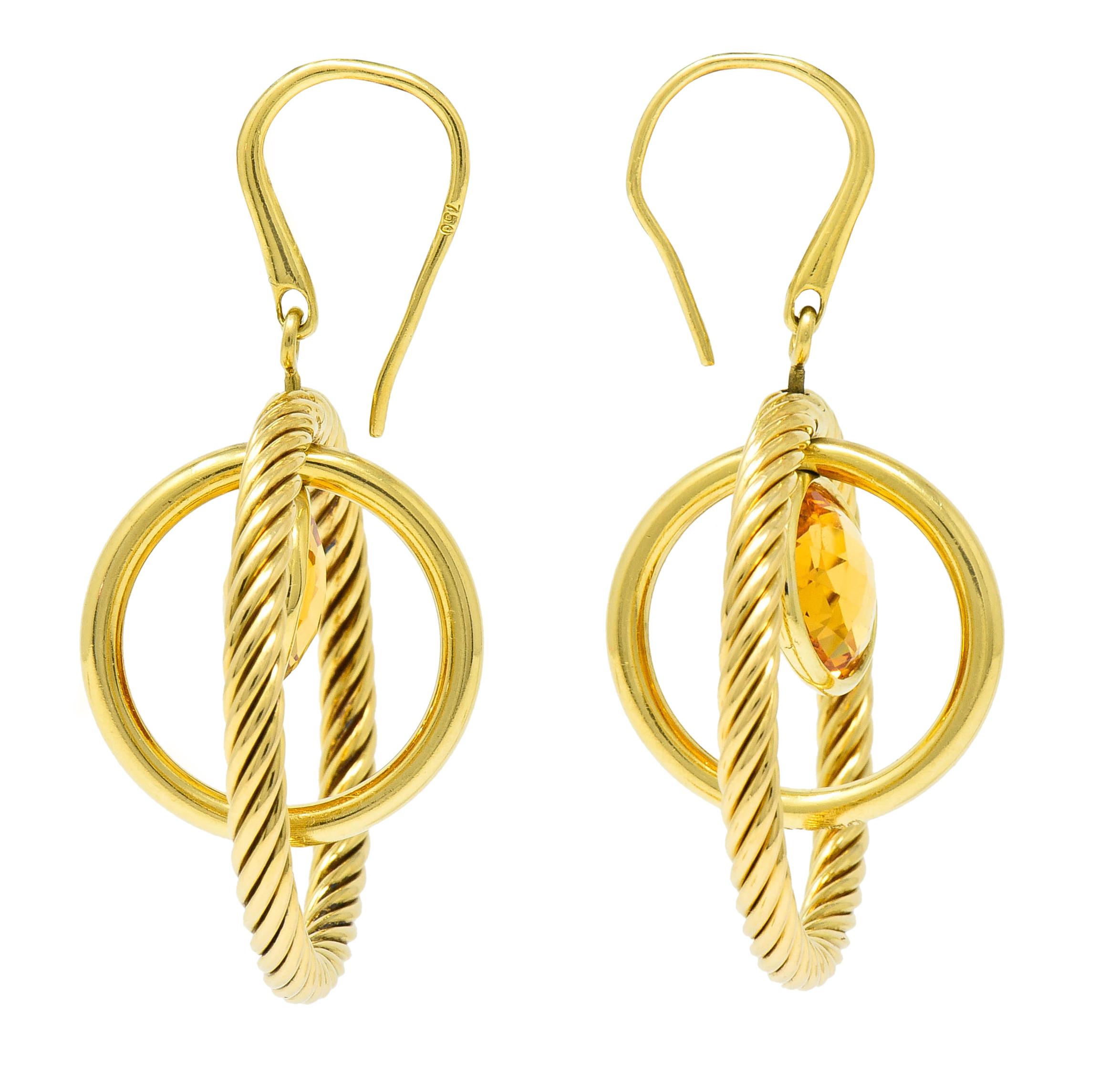 Earrings are designed as concentric circles, polished and twisted cable, that rotate on an axis

Centering 9.5 mm round checkerboard cut citrine; well-matched and light orange in color

Bezel set and also articulated

Completed by shepherd hook ear