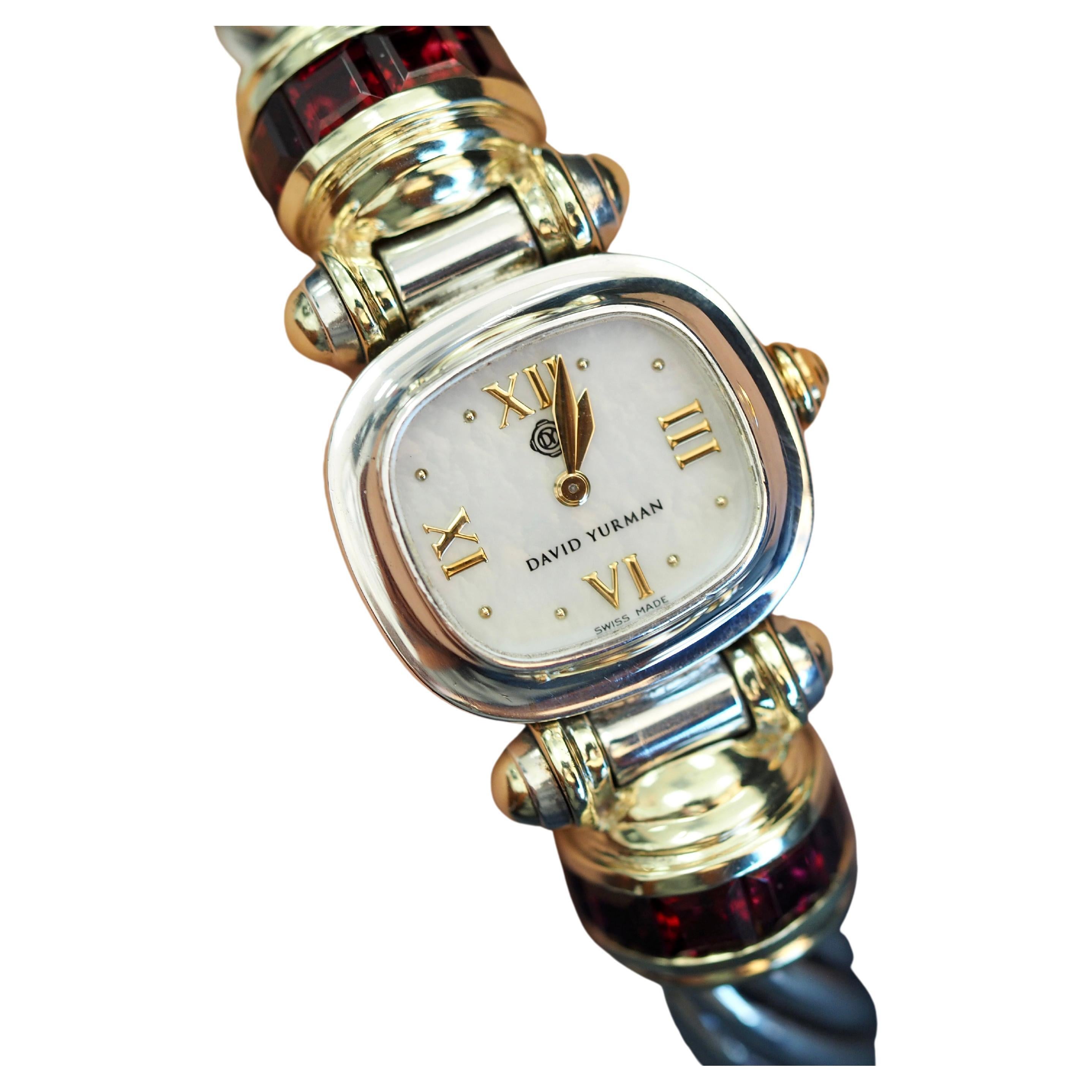 Diese unglaubliche Uhr ist eine klassische Kabelkette David Yurman. Die Uhr ist mit wunderschönen Granaten an der Seite und mit Details aus 14-karätigem Gelbgold verziert, die die Uhr auszeichnen. Das Band ist eine klassische Kabelkette mit einem