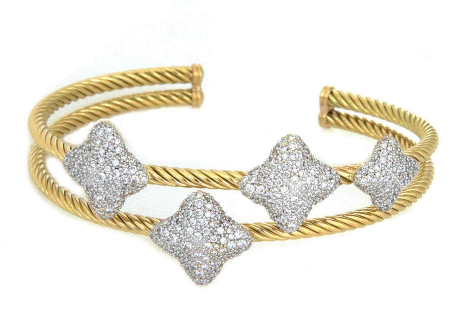 Elite and authentic by David Yurman from his Quatrefoil Collection. This gorgeous cuff bracelet is crafted from 18k yellow and white gold featuring a split double cable wire band in the cuff style. Attached to one cable band on the front center are
